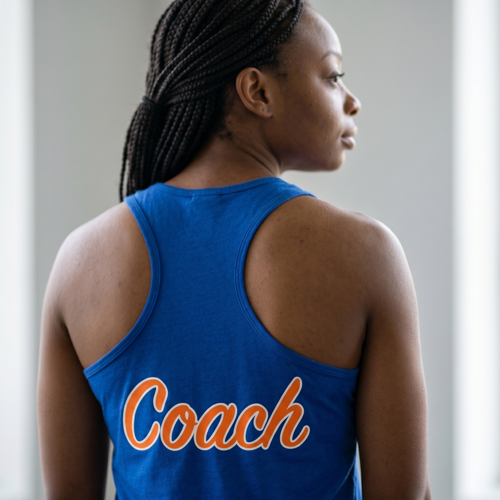 Back view of blue Bolt Fitness coach racerback tank with orange and white Coach lettering