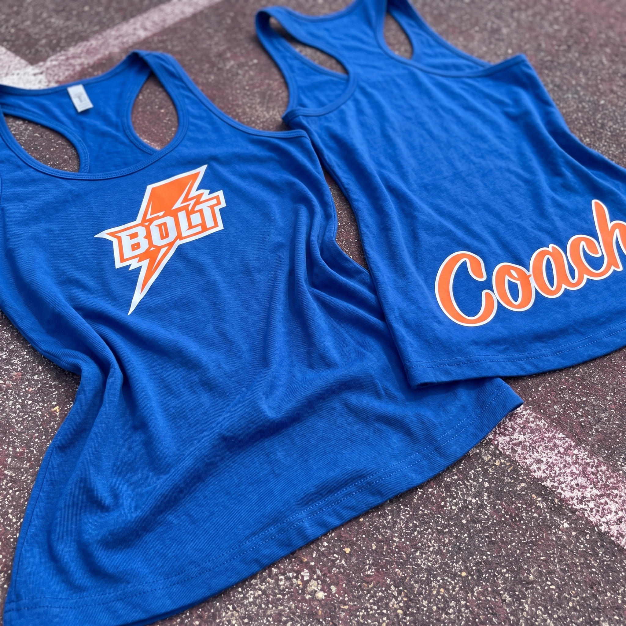 Bolt Fitness collection with blue coach tanks, orange tee, sublimated blue hoodie, and blue joggers laid flat