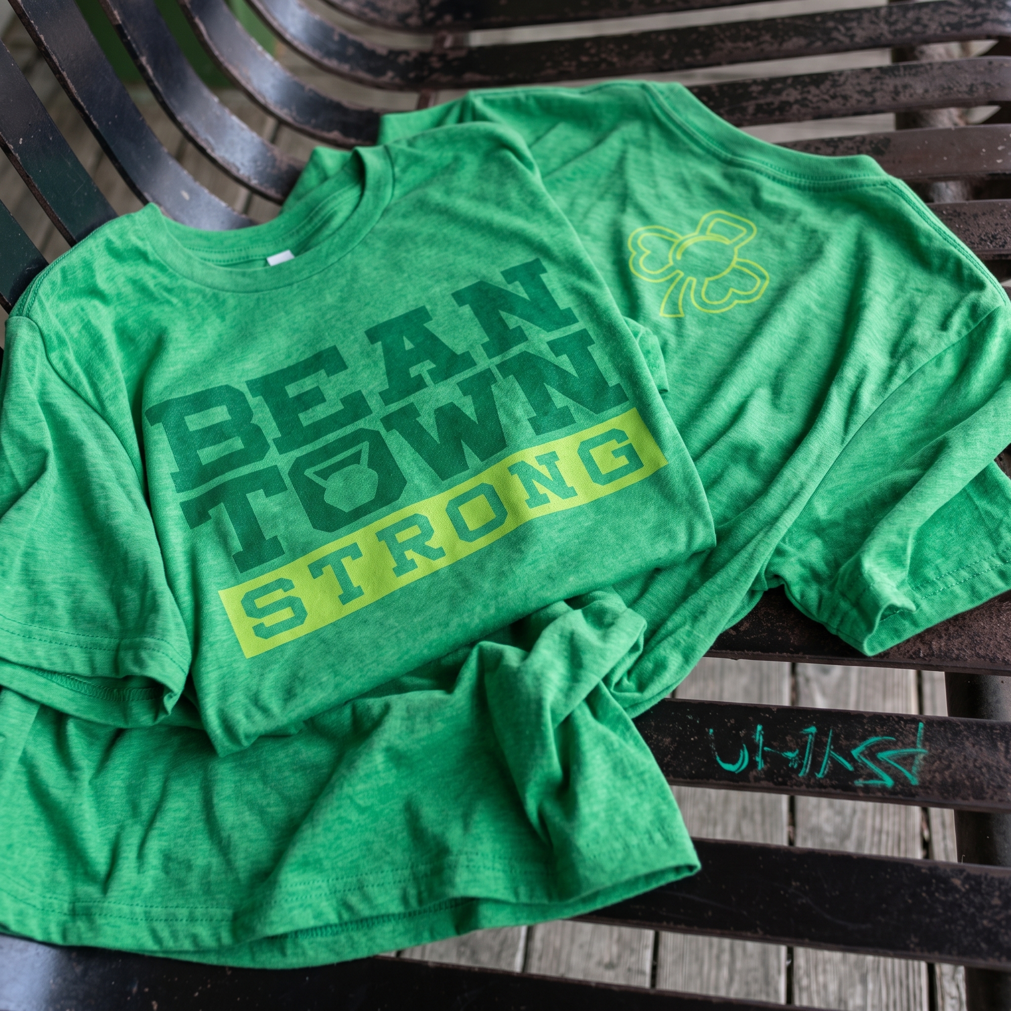 Beantown Strength green tee with bold wordmark and shamrock back detail