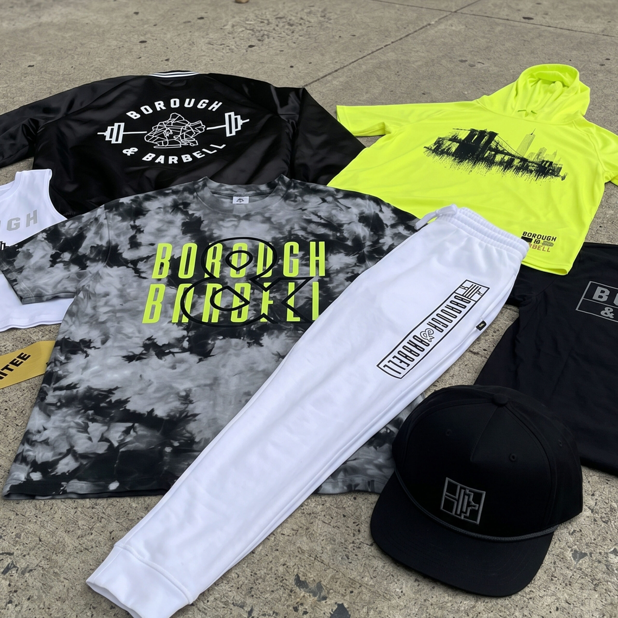 Borough & Barbell apparel collection flat lay with hoodie, jogger, hat, and tees