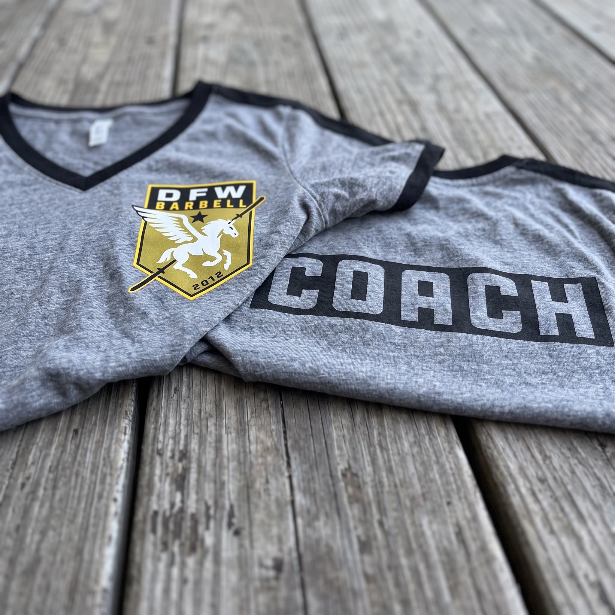 DFW Barbell apparel lay flat with neon hoodie, tees, beanie, and joggers