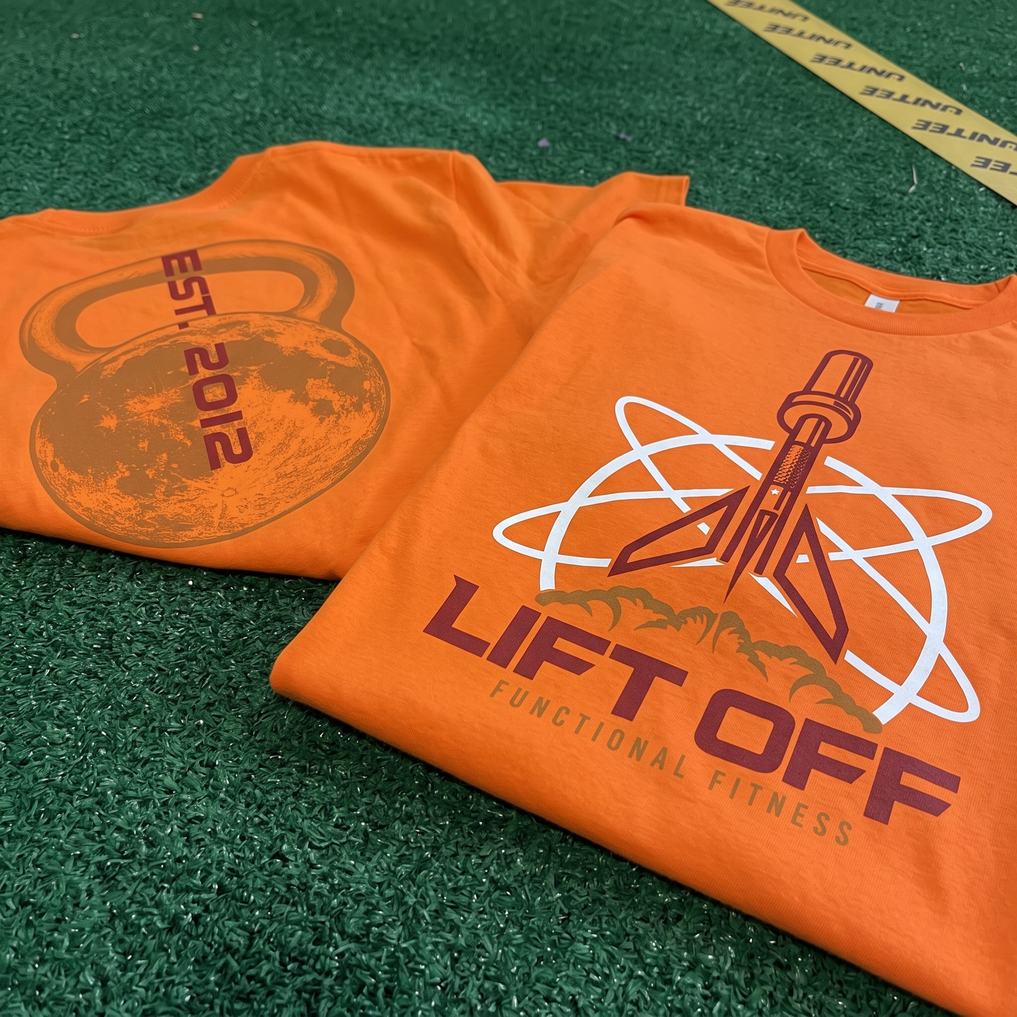 Lift Off Functional Fitness orange tees with rocket and kettlebell graphics