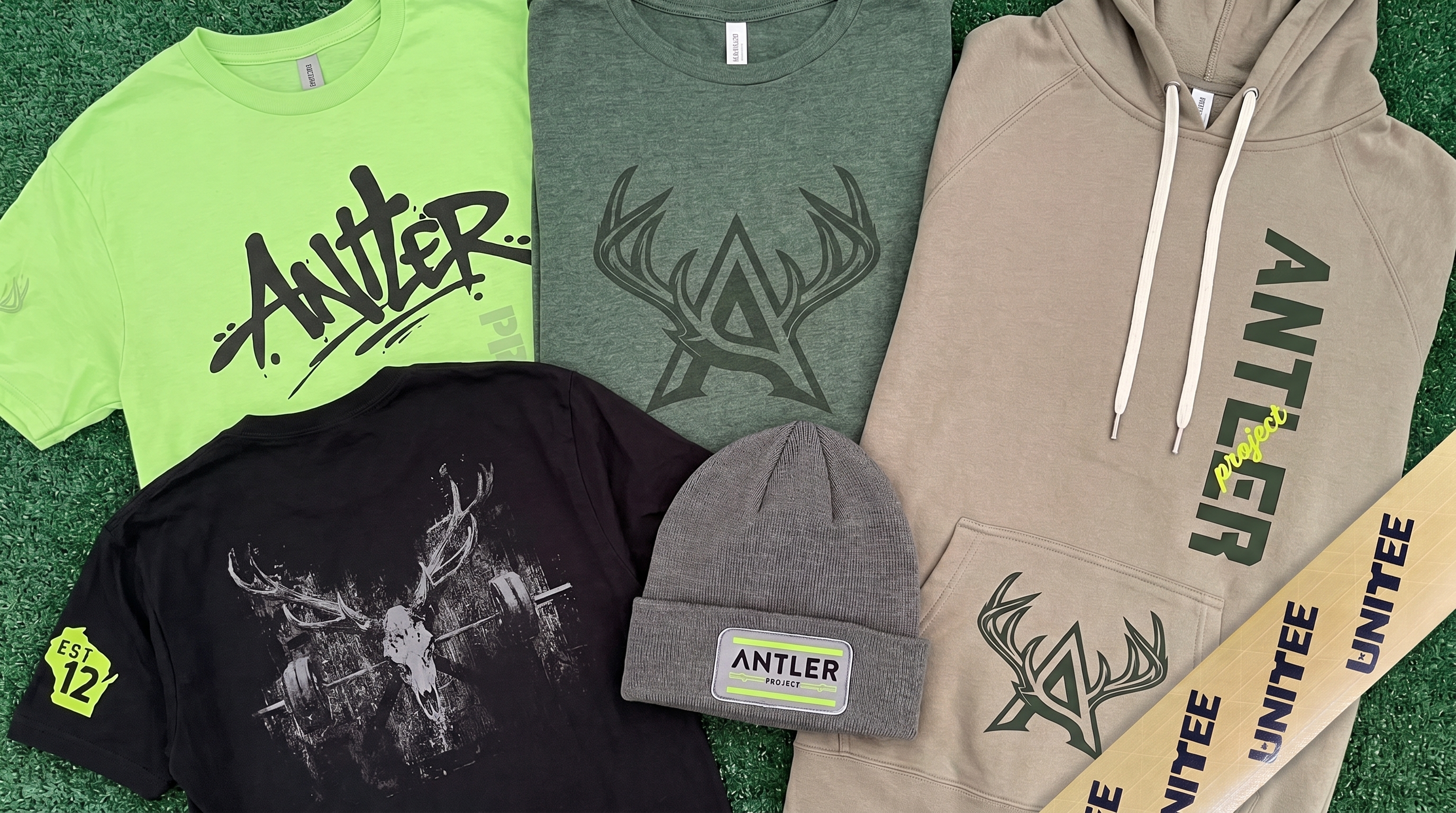 Full Antler Project Milwaukee apparel collection with tees, hoodie, beanie, deer skull graphic, antler mark, and lime green accents