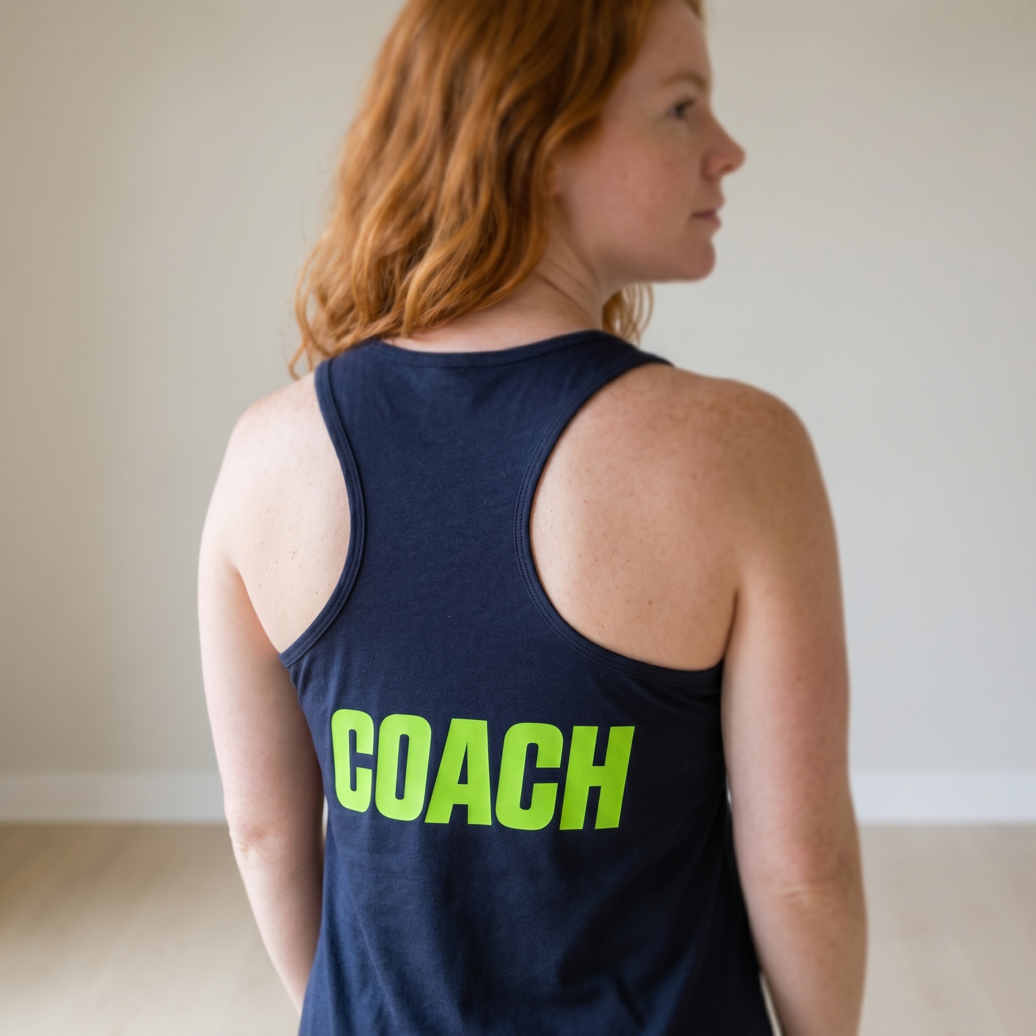 Back of navy Twin Cities Fitness coach racerback tank with neon green coach print