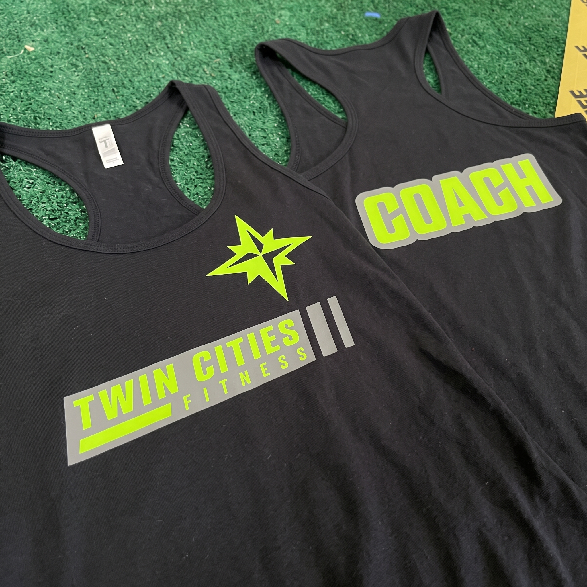 Twin Cities Fitness black coach tank tops with neon green and grey graphics