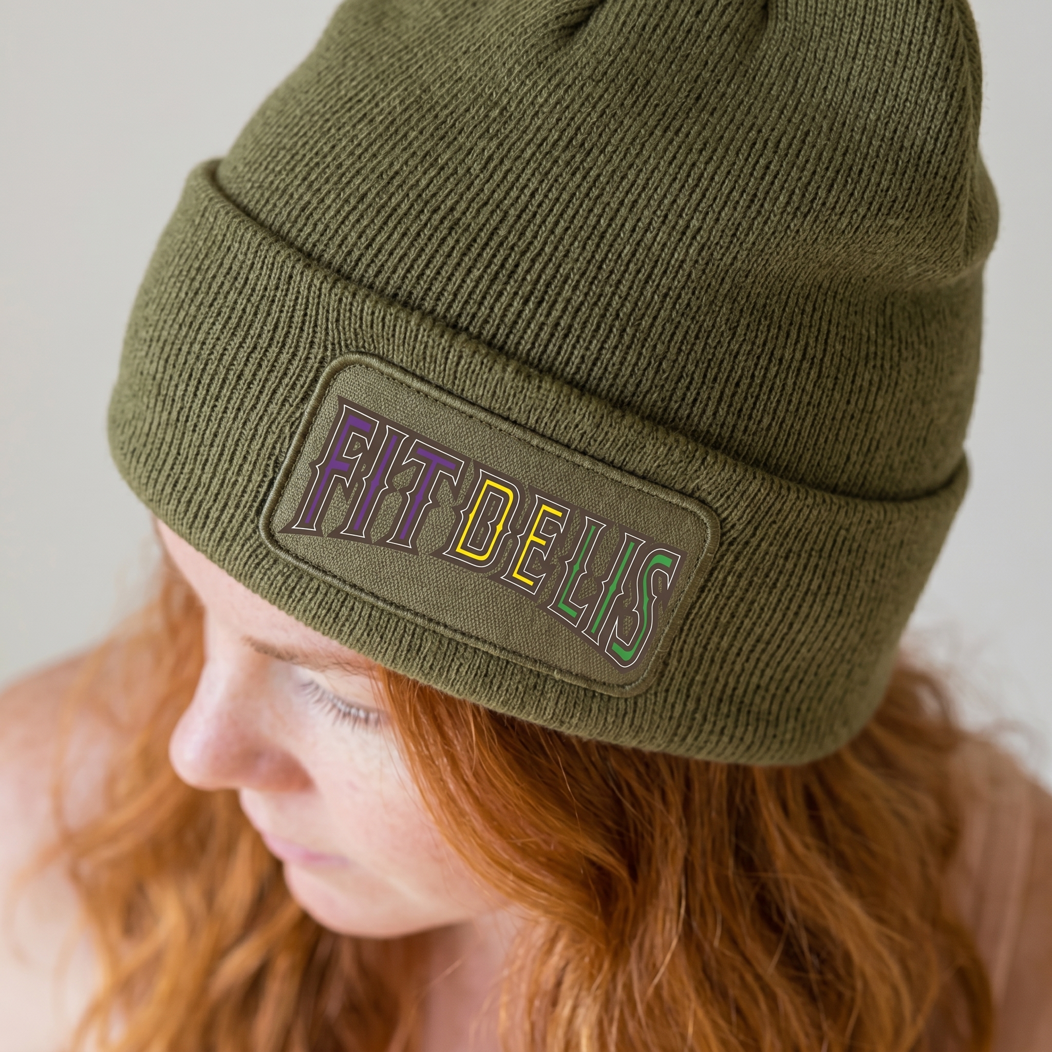 Olive Fit De Lis beanie with embroidered patch in purple, yellow, and green