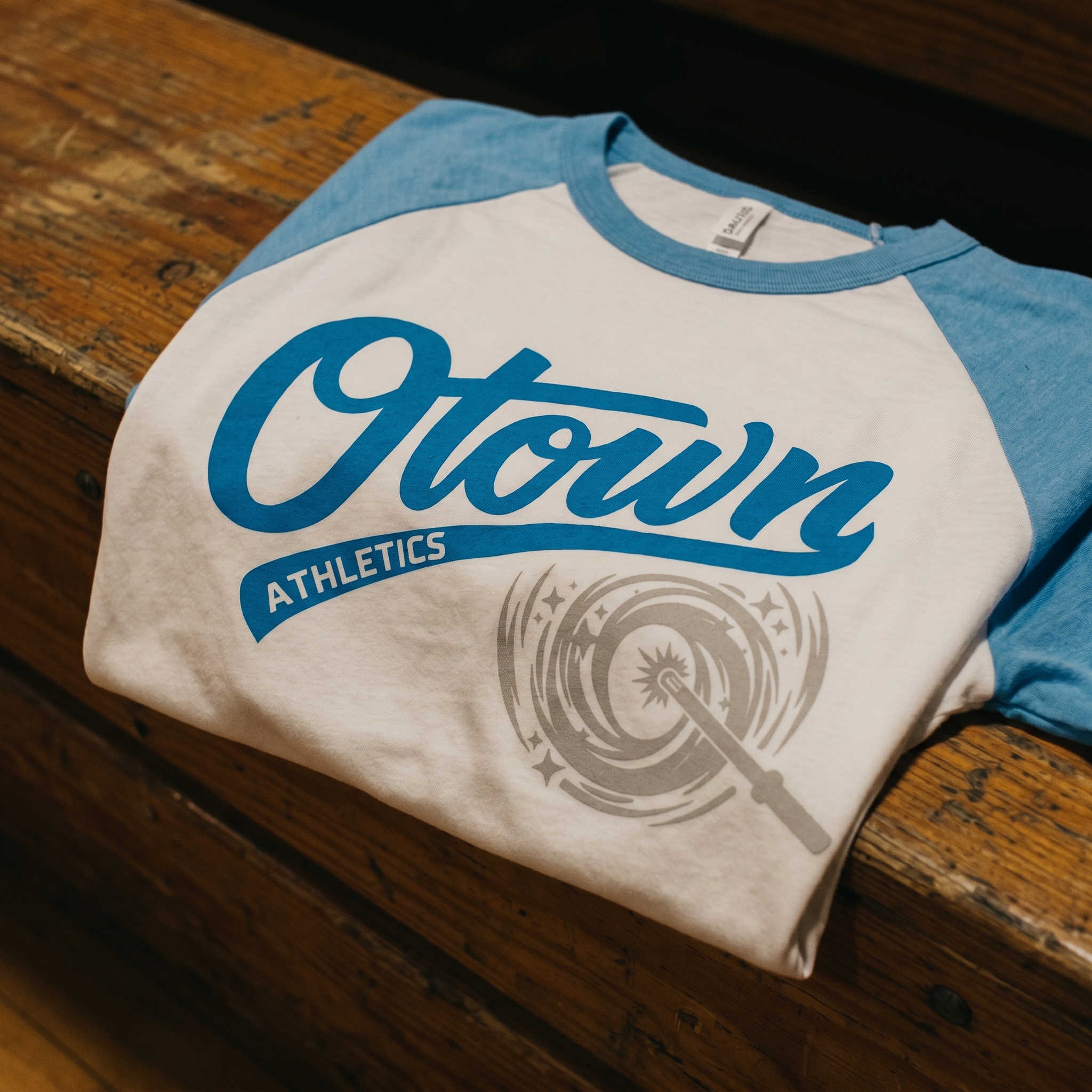 O Town Athletics white and blue raglan with large teal script logo and grey swirl graphic