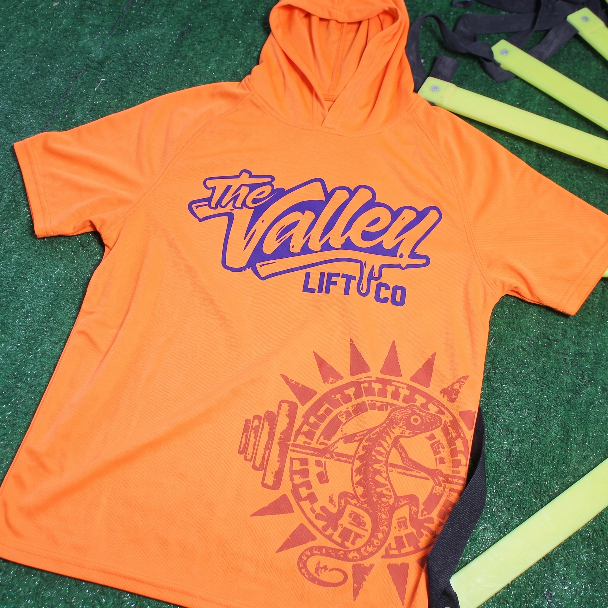 Bright orange short sleeve training hoodie for The Valley Lift Co with large script wordmark and oversized lizard sunburst graphic