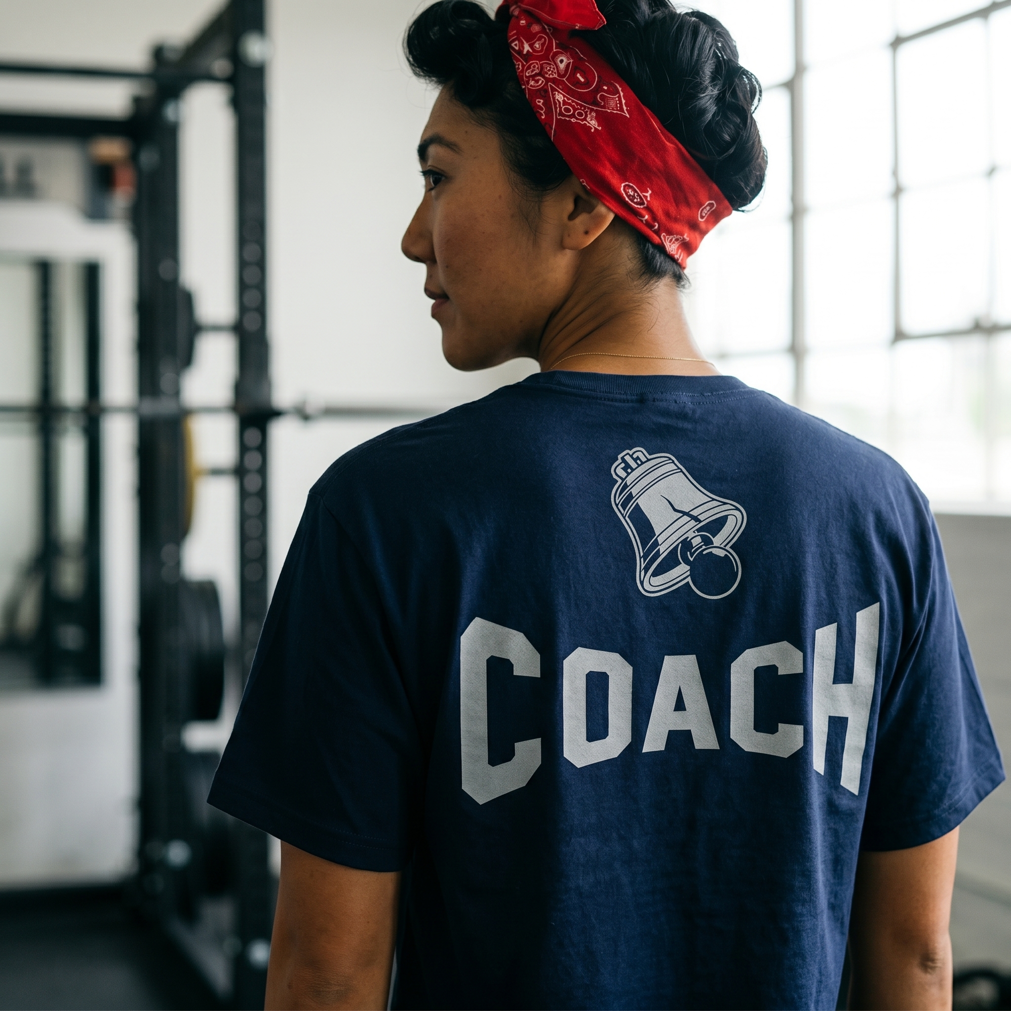 Back view of navy Independence Barbell coach tee with silver Coach lettering and Liberty Bell icon