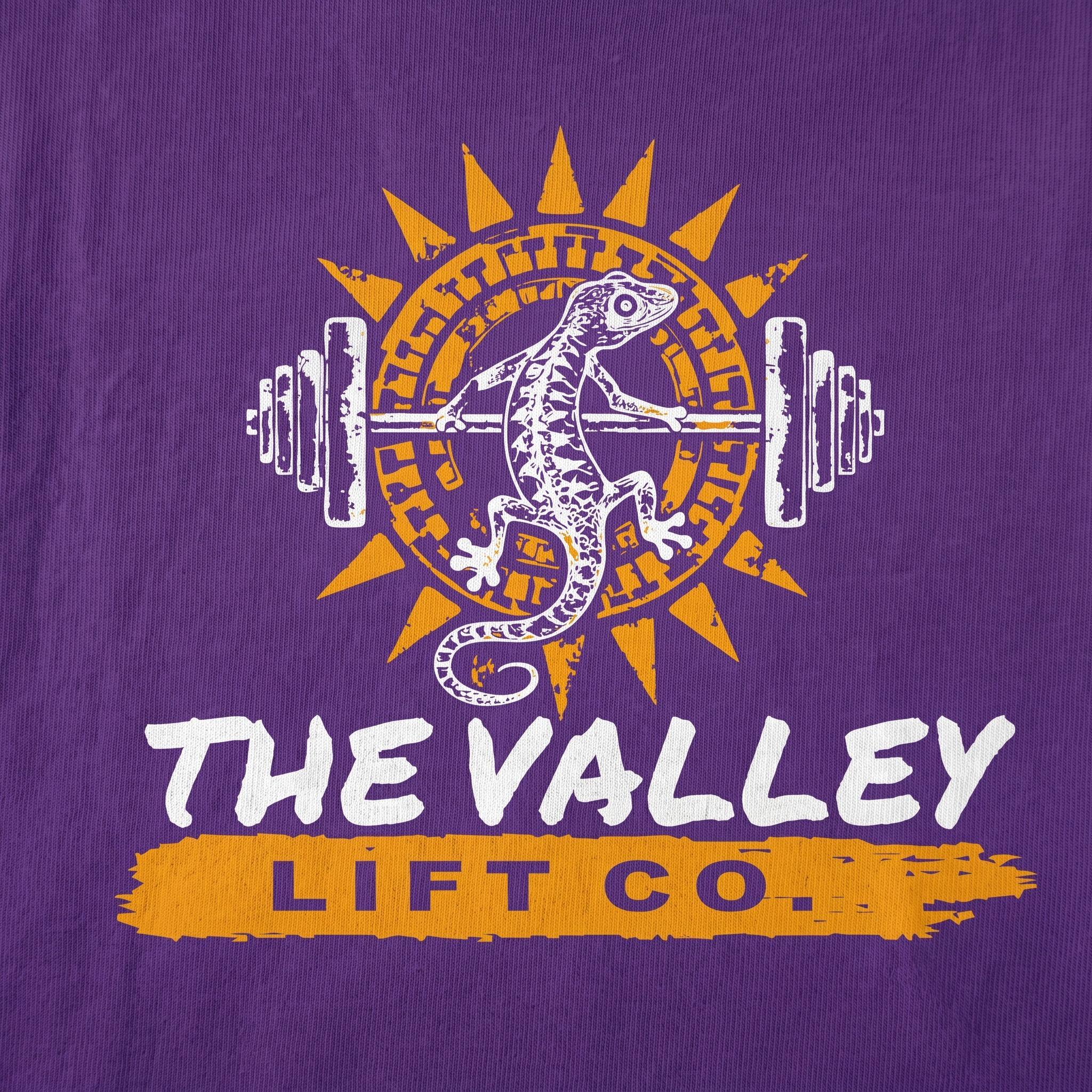 Close-up of The Valley Lift Co screen printed lizard, sunburst, and barbell logo on purple fabric