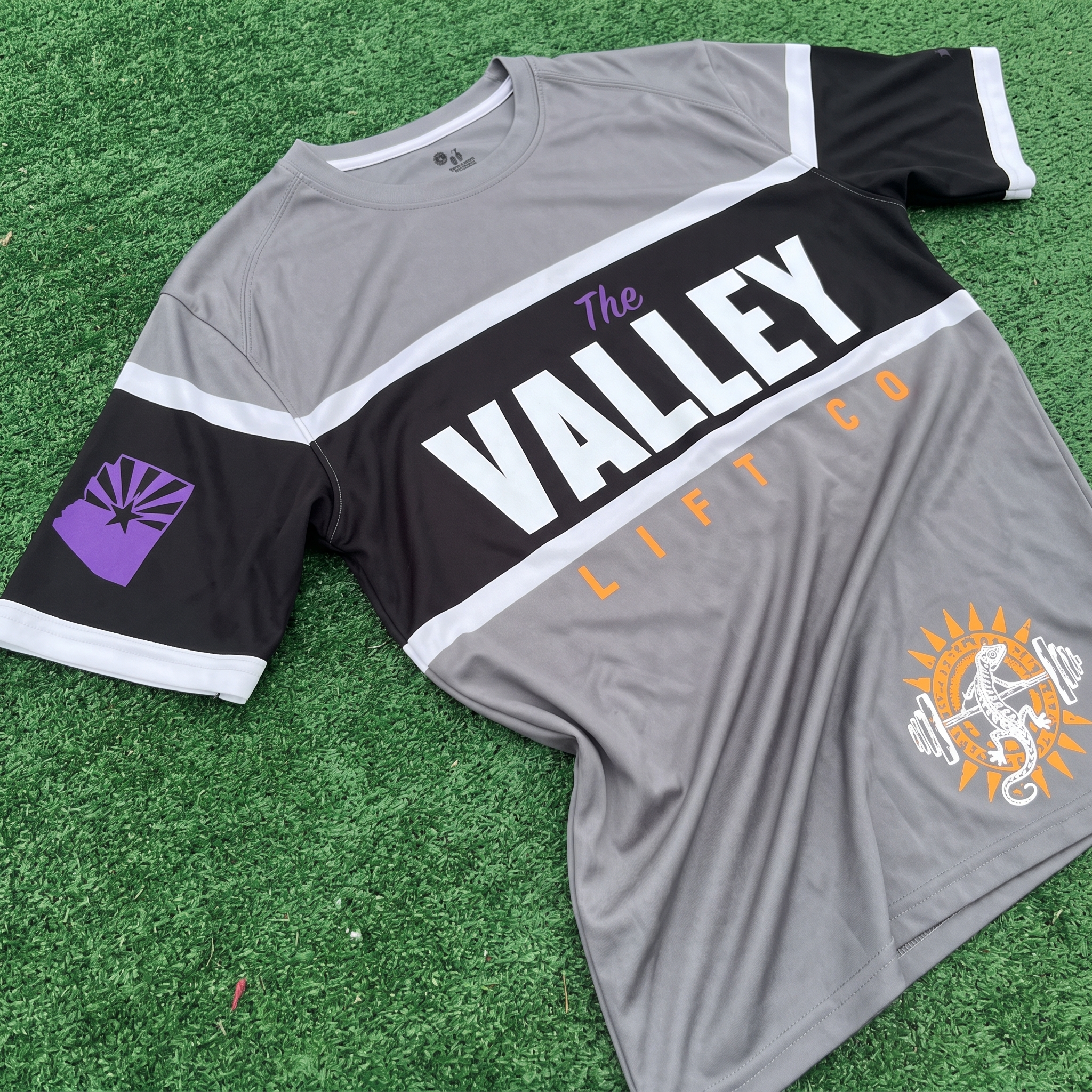 Grey and black performance jersey for The Valley Lift Co with large chest wordmark, Arizona sleeve badge, and lower lizard sunburst graphic