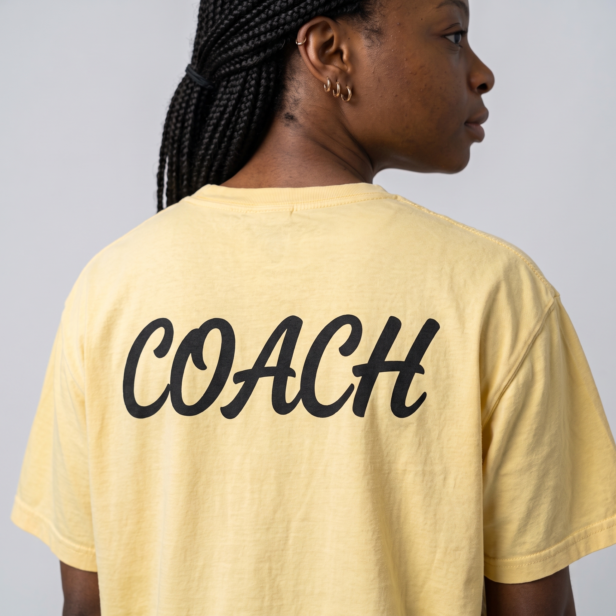 Back view of yellow Salty State Strength Co. coach tee with large black Coach script