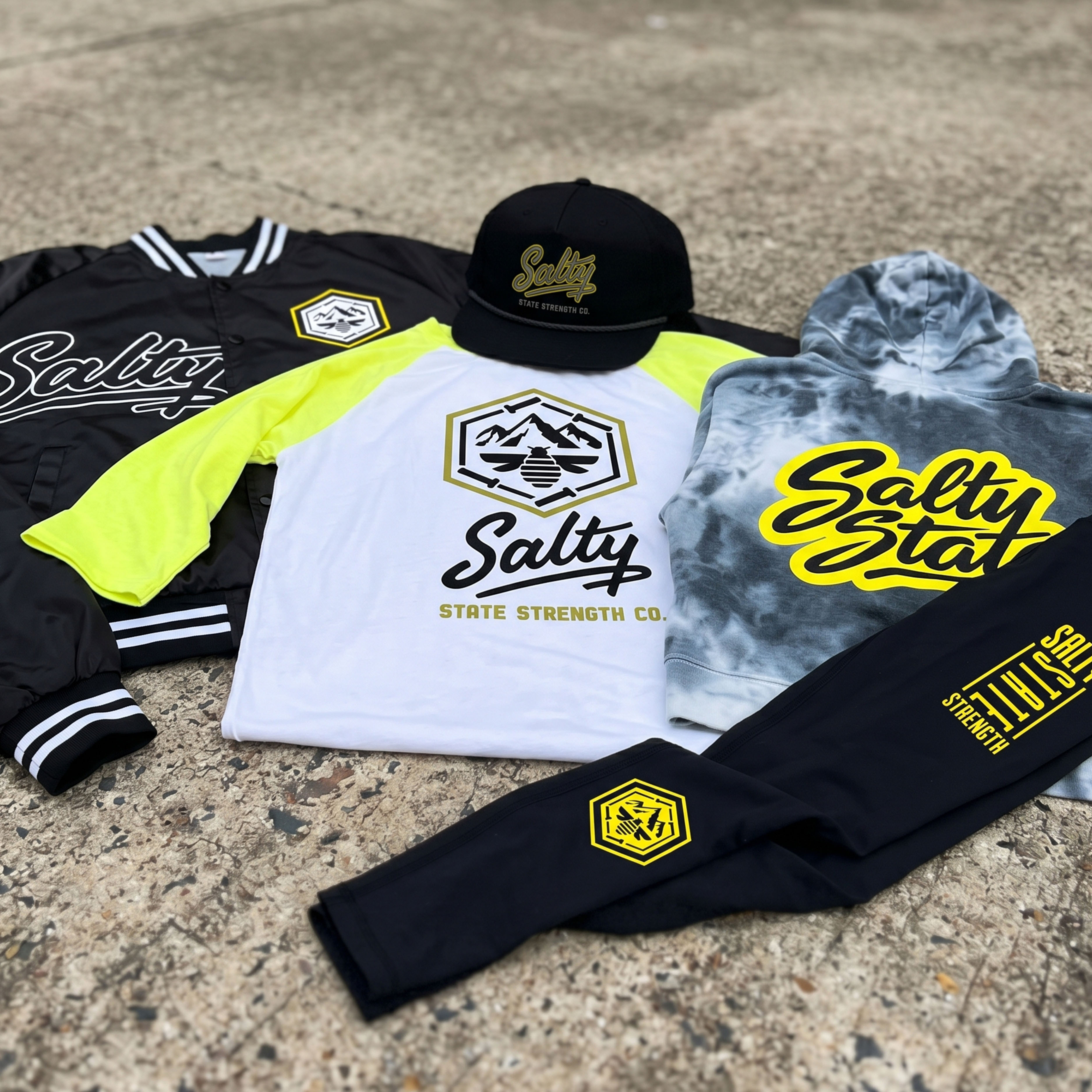 Full Salty State Strength Co. apparel collection with jacket, raglan tee, hoodie, leggings, hat, and yellow Salt Lake City design system