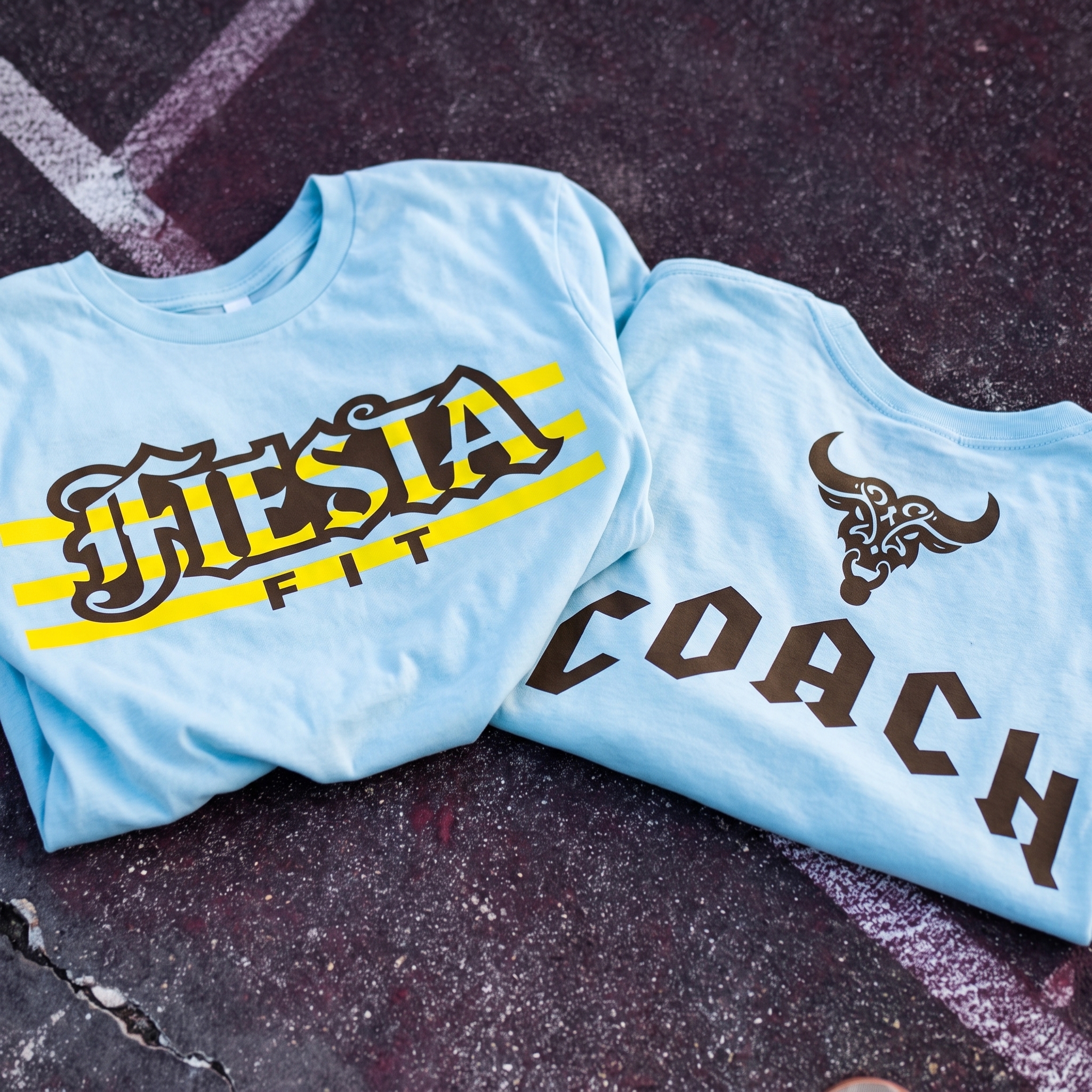 Blue Fiesta Fitness coach tee with black coach lettering and bull neck mark