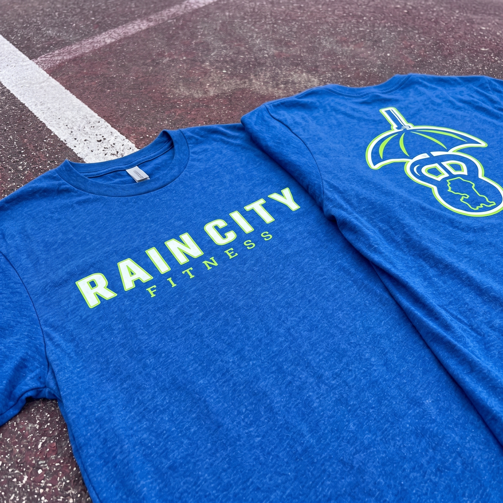 Blue Rain City Fitness tee with front wordmark and back umbrella kettlebell Seattle icon