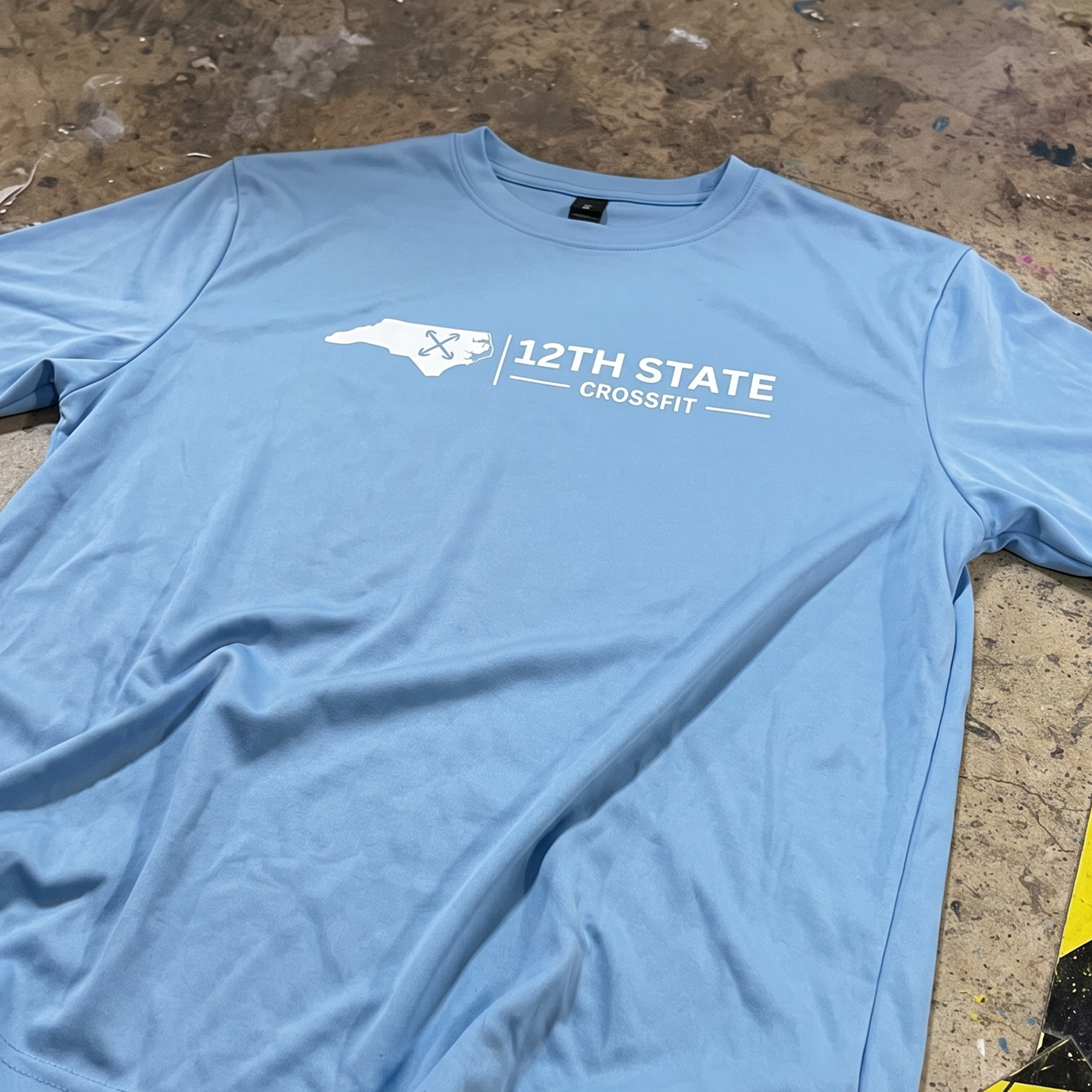 Powder-blue long-sleeve shirt with a white North Carolina silhouette and 12th State CrossFit front print.