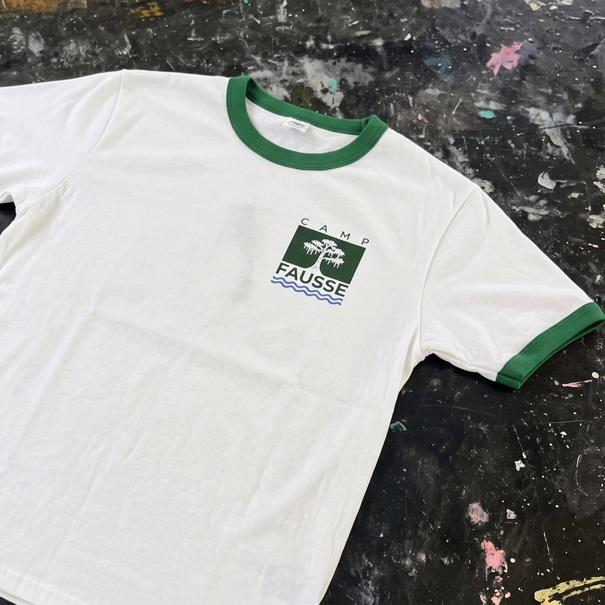 White ringer T-shirt with green trim and small Camp Fausse cypress logo.