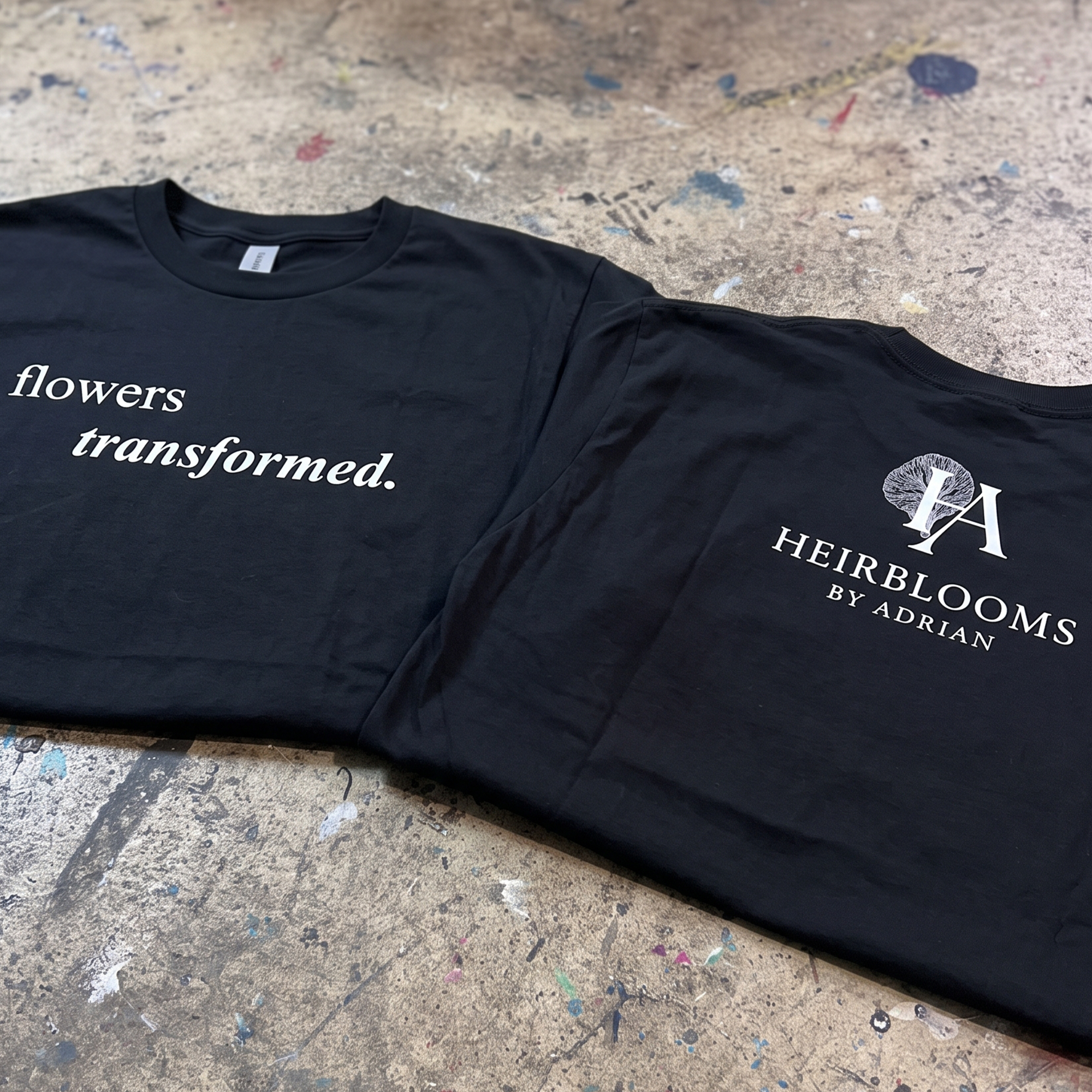 Two black T-shirts with white floral serif graphics and logo prints.