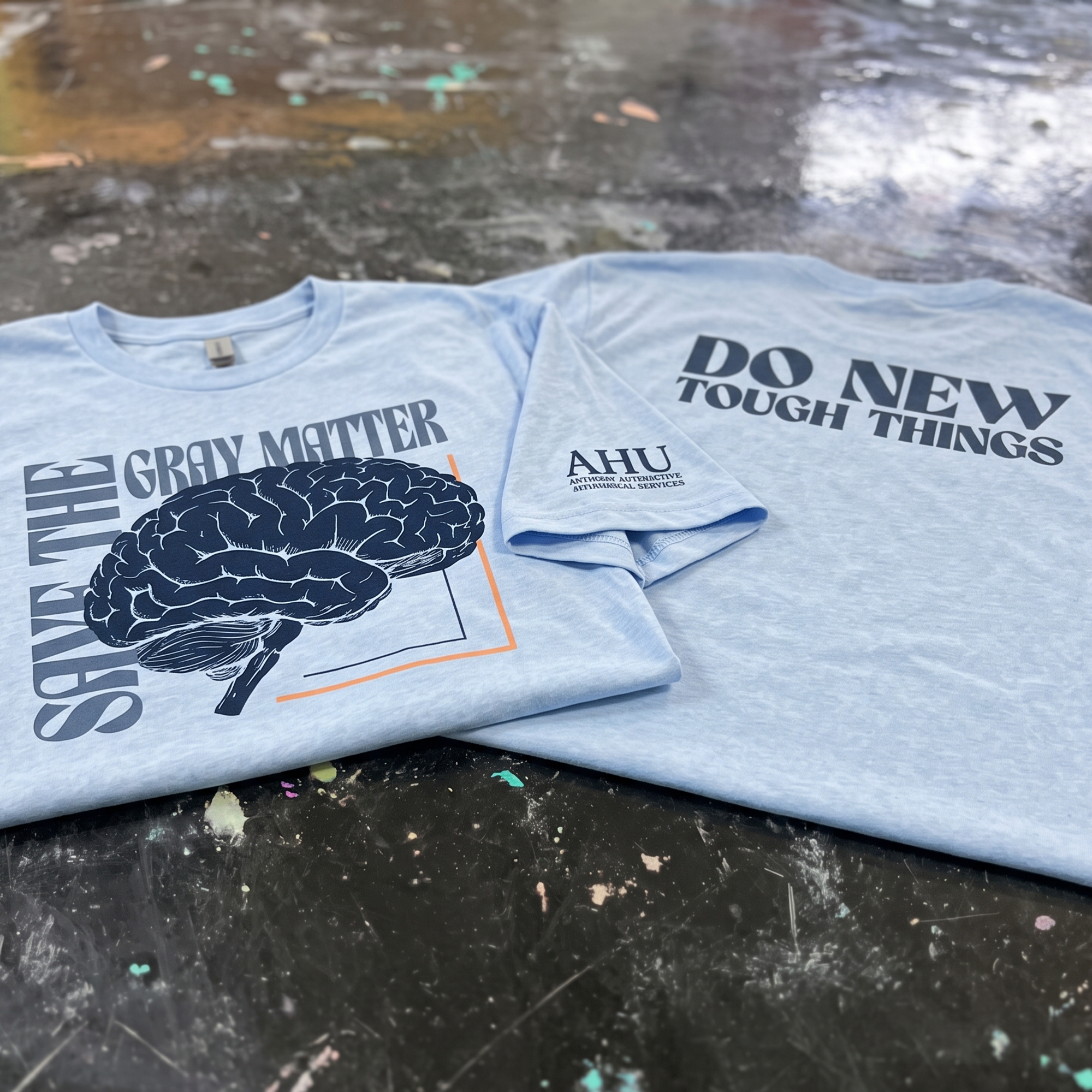 Light blue CrossFit Lockhart tee with navy brain illustration, gray matter text, and orange linework.