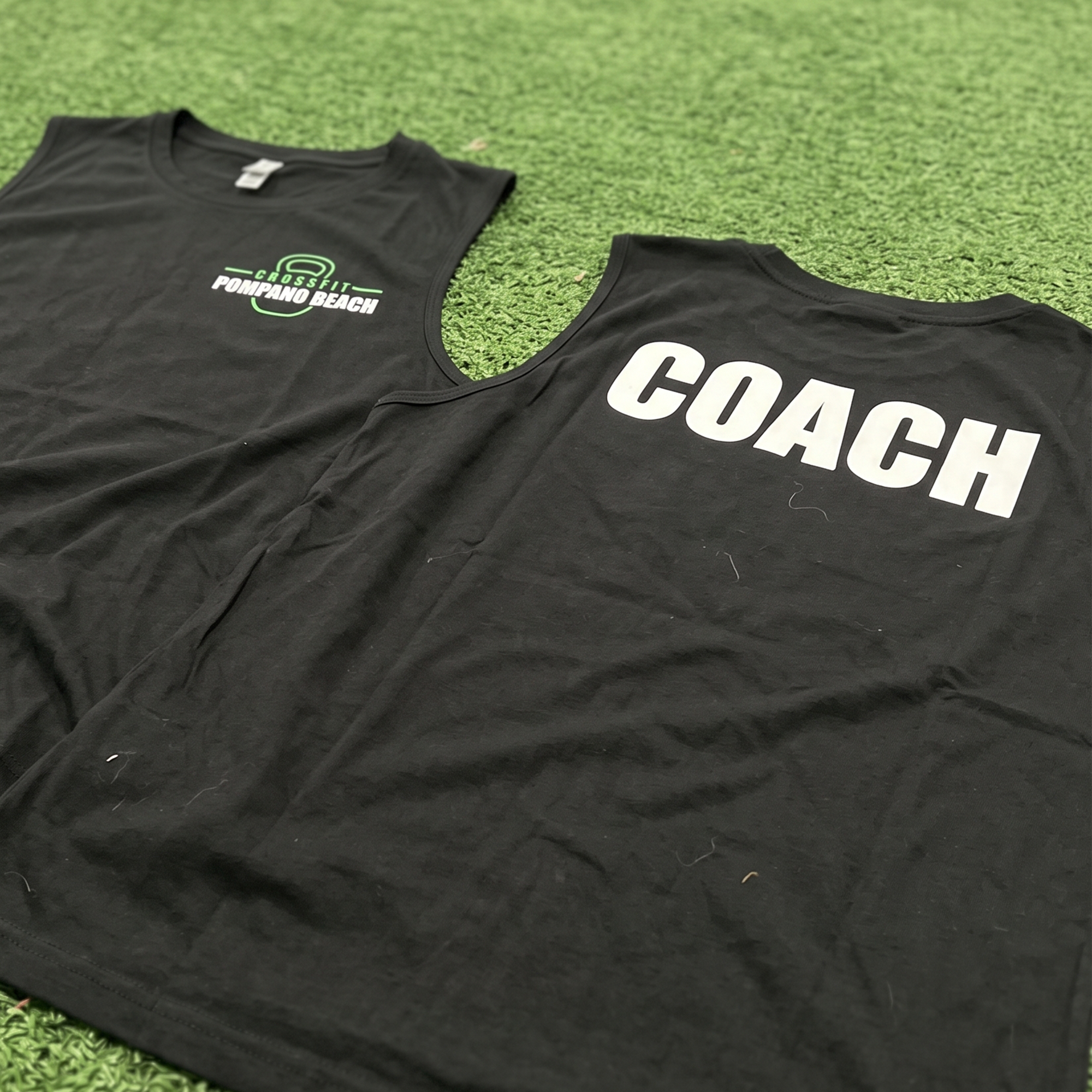 Black performance shirts with green front logo and oversized white coach back print.
