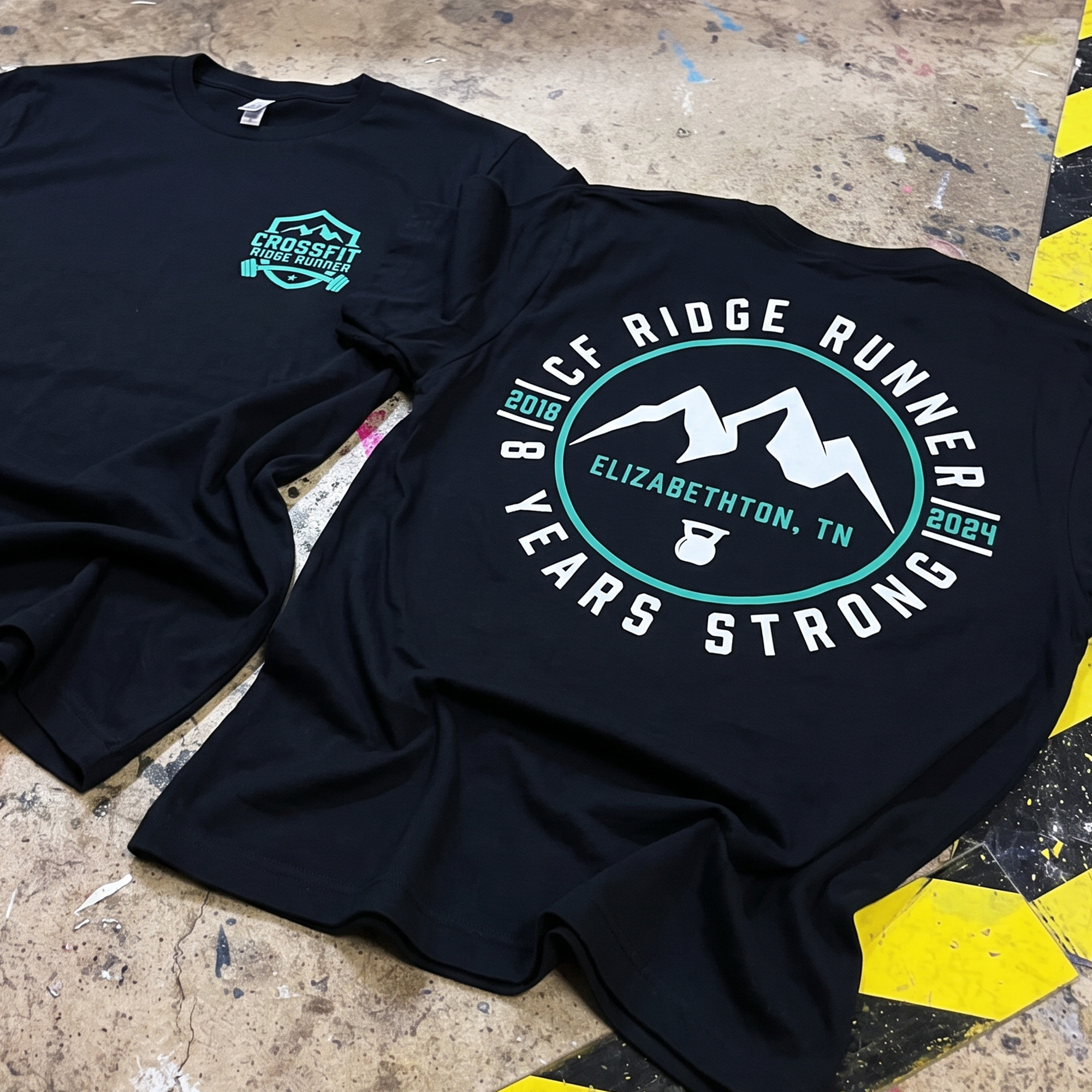 Black CrossFit Ridge Runner anniversary shirt with teal chest badge and mountain back graphic.