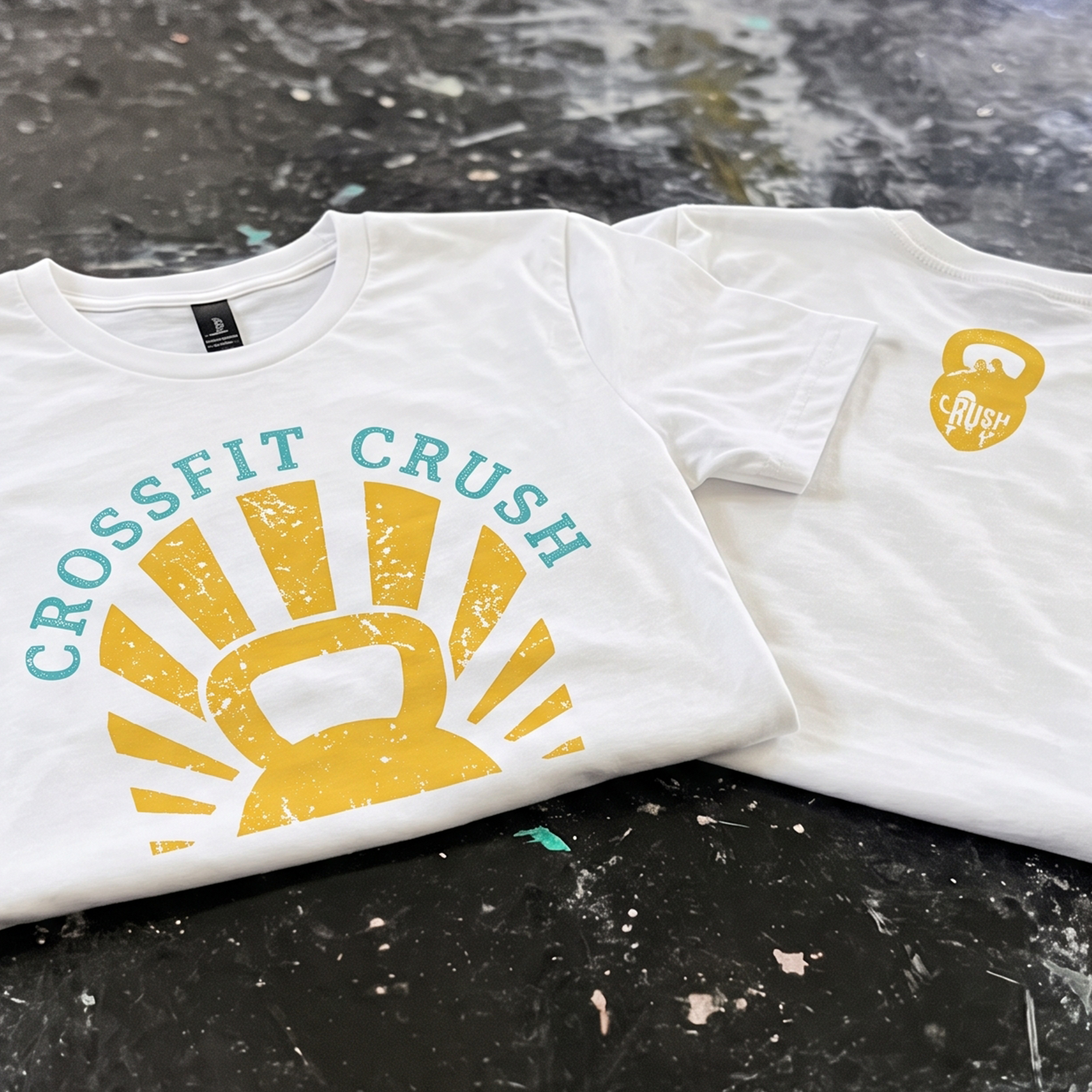 White CrossFit Crush T-shirts with distressed yellow kettlebell sunburst graphic and turquoise lettering.