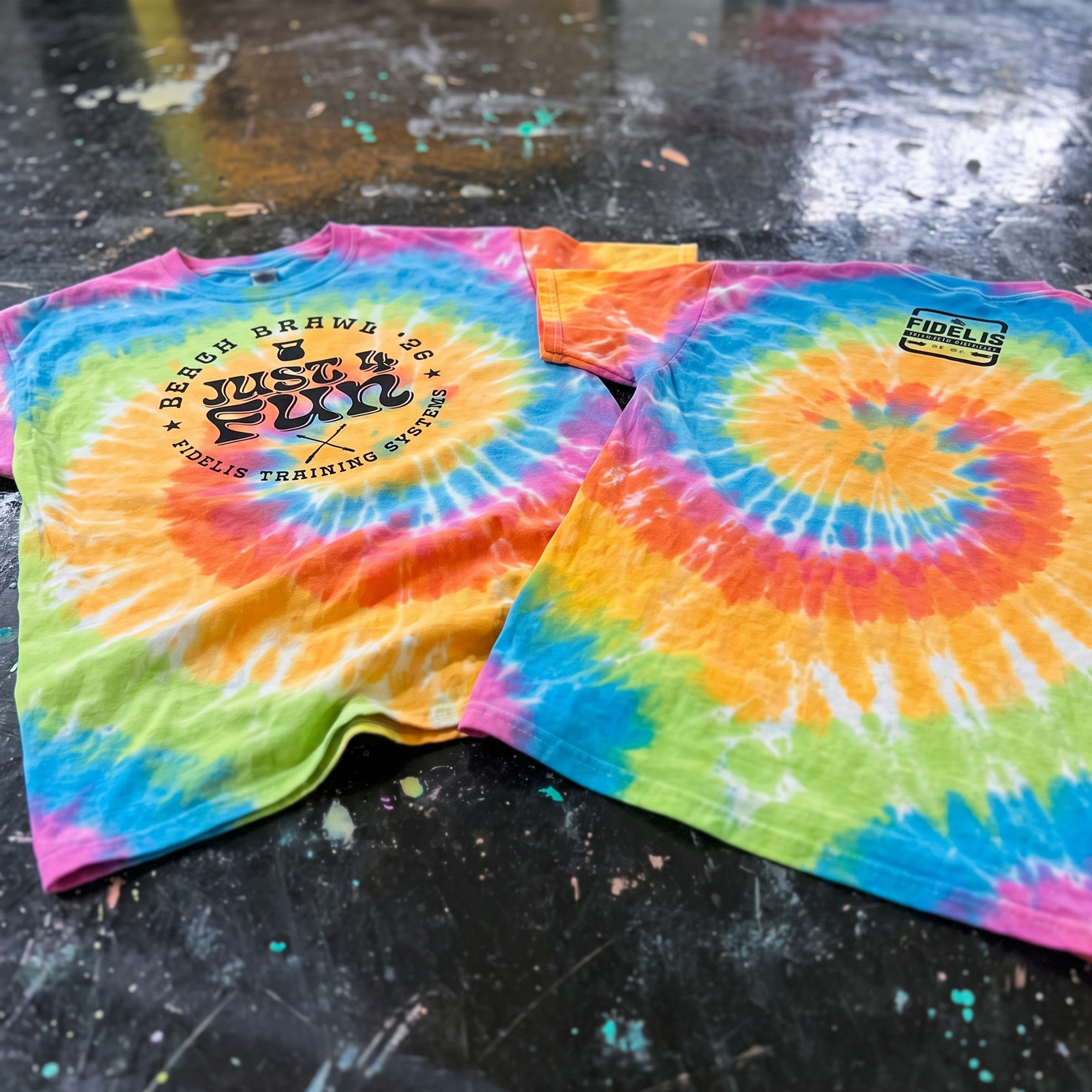 Rainbow tie-dye Fidelis tees with a circular Beach Brawl graphic and chest logo.