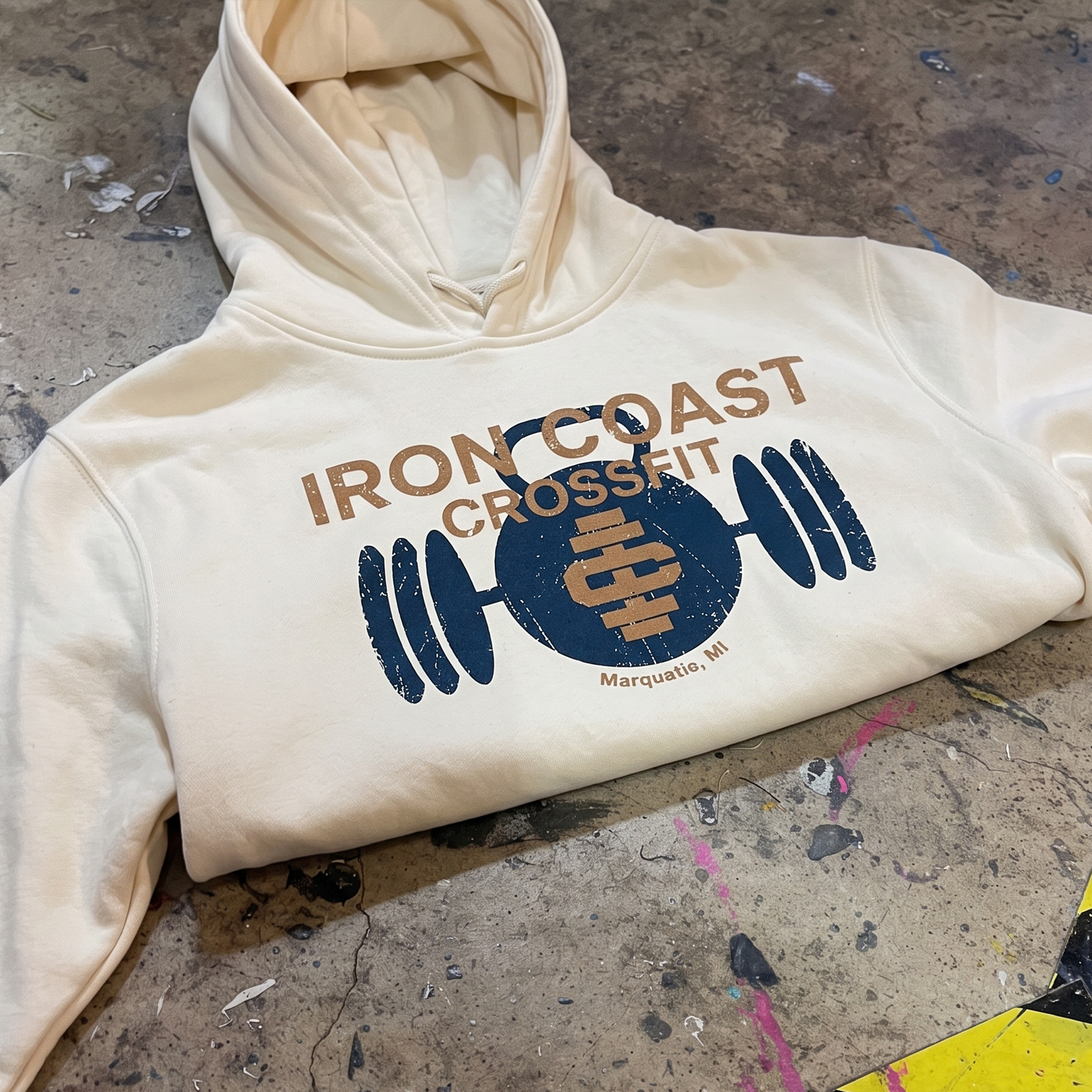 Cream hoodie with distressed navy and tan Iron Coast CrossFit barbell graphic.