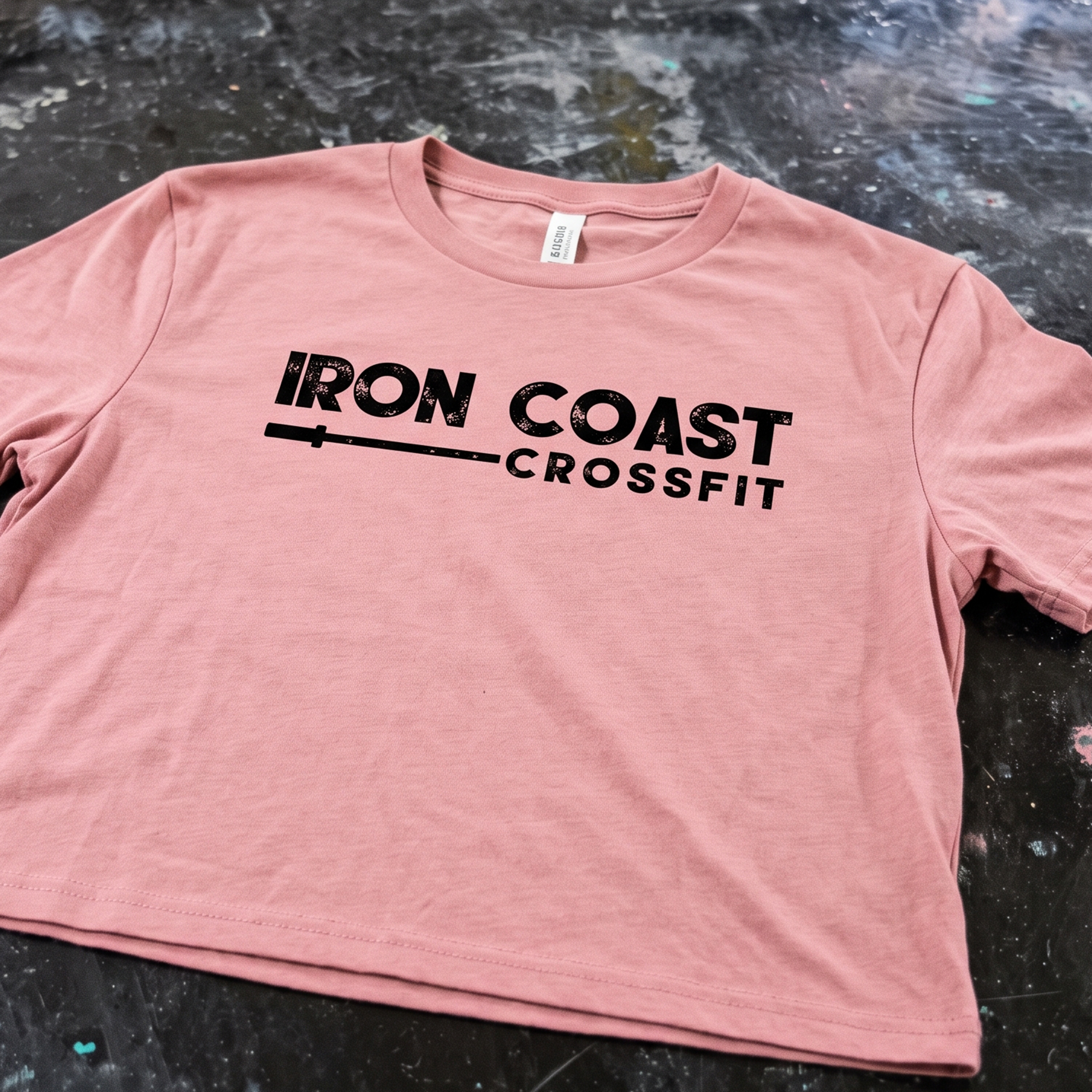Dusty rose cropped T-shirt with distressed black Iron Coast CrossFit lettering and barbell graphic.