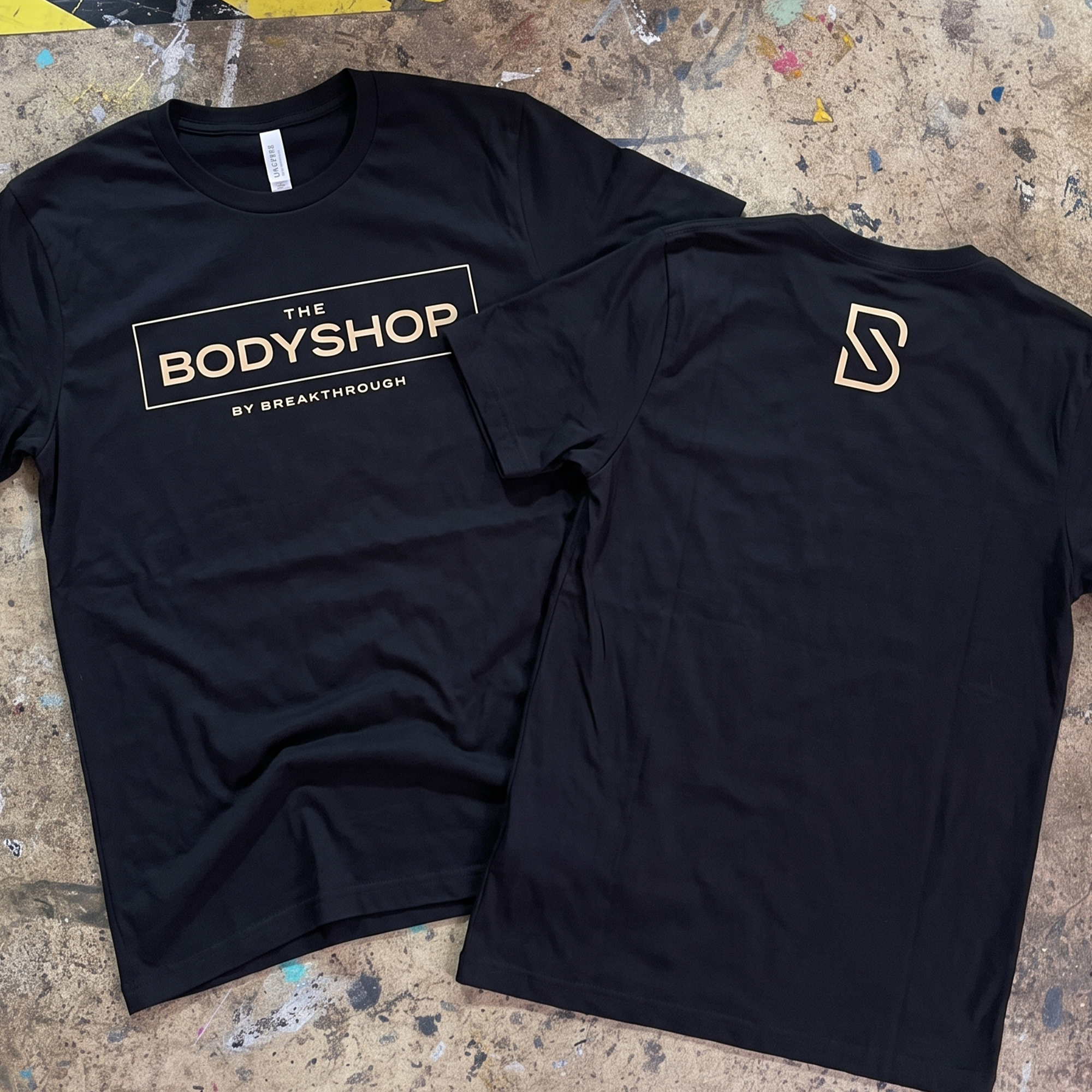 Black performance tees with cream Body Shop front wordmark and back monogram.