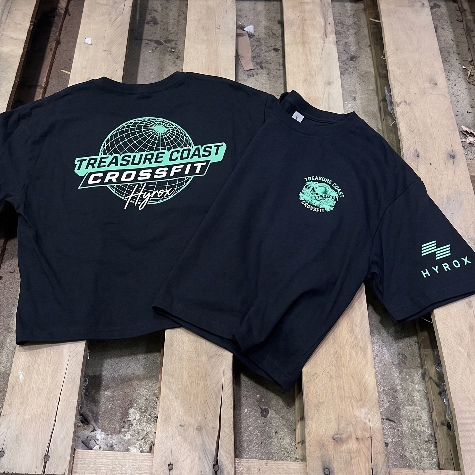 Black Treasure Coast CrossFit HYROX tee with mint globe back print, chest graphic, and sleeve logo.