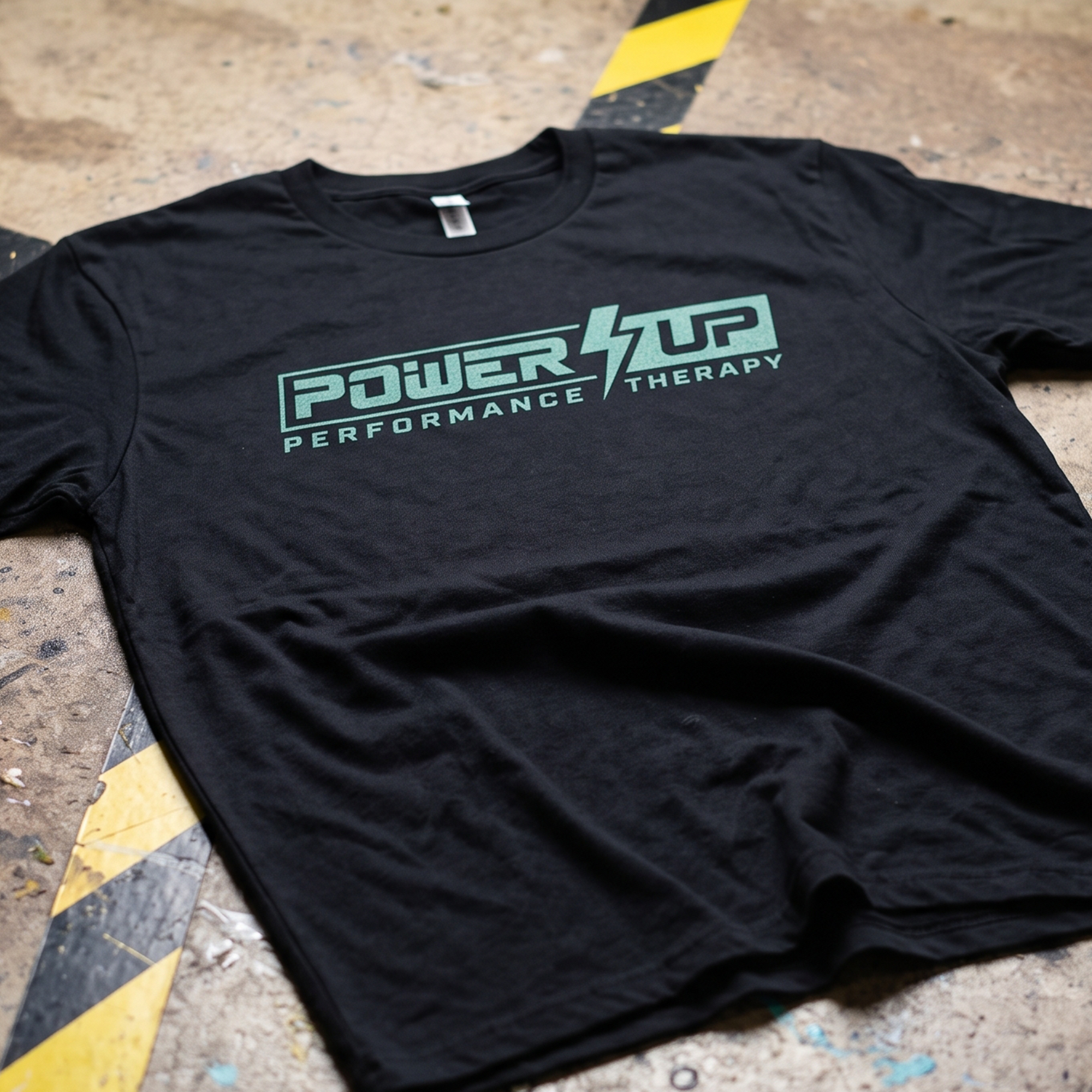 Black tee with mint Power Up Performance Therapy lightning logo across the chest.