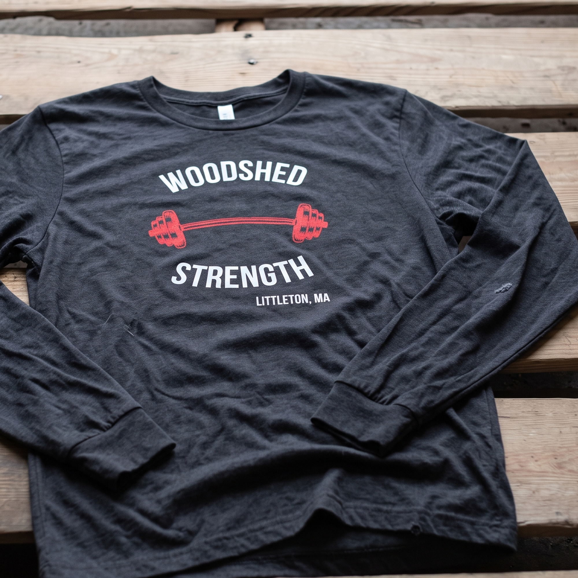 Black long-sleeve Woodshed Strength shirt with white lettering and red barbell graphic.