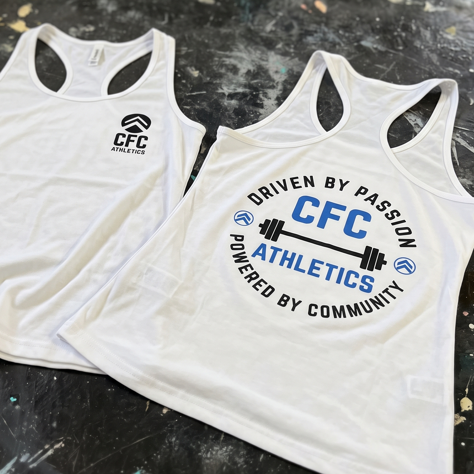 White CFC Athletics racerback tanks with small chest logos and large blue-and-black barbell back print.