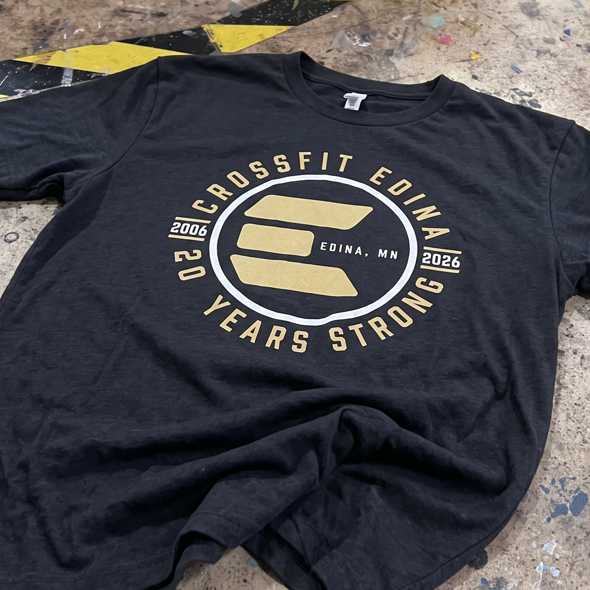Black T-shirt with gold and white CrossFit Edina 20 Years Strong anniversary graphic.