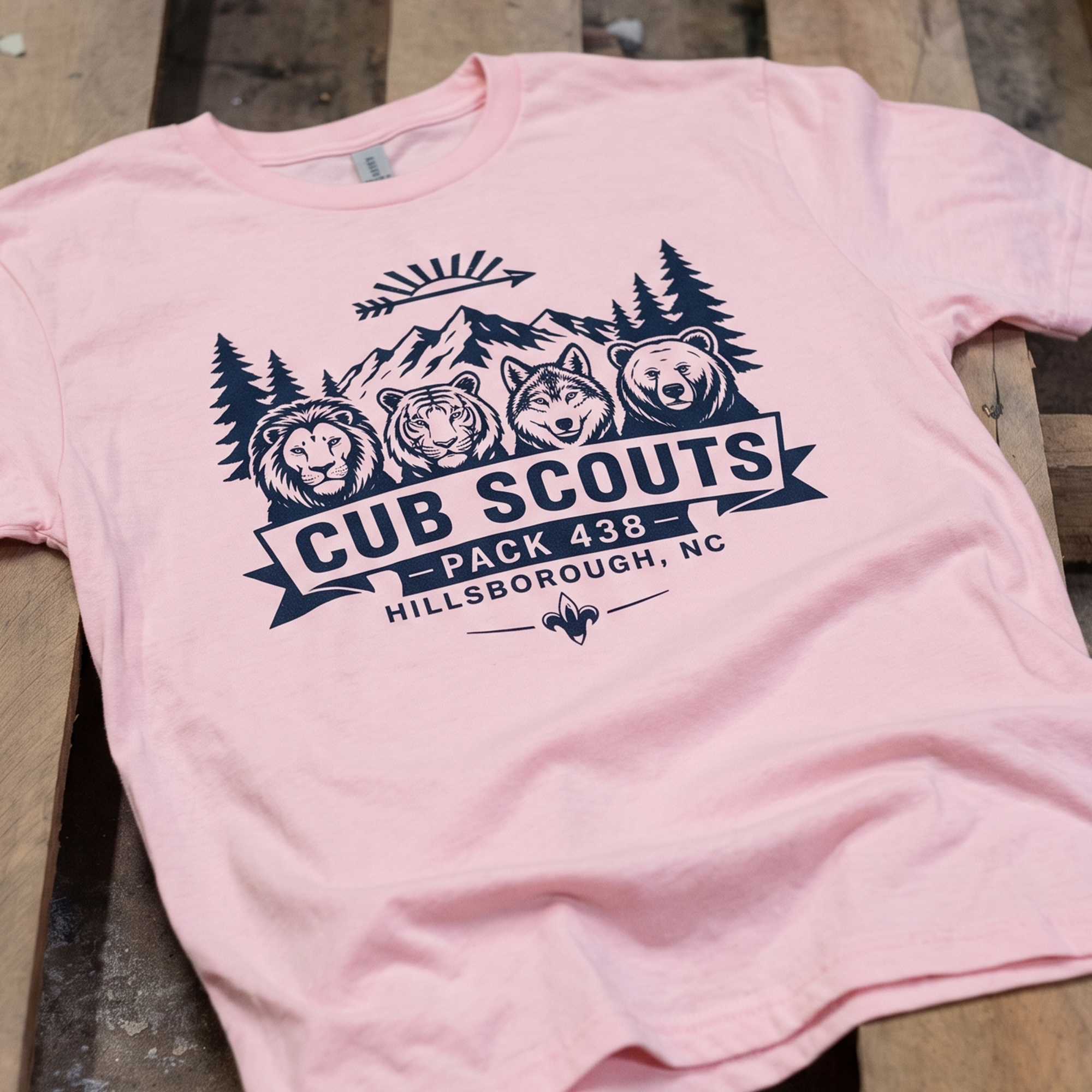 Light pink T-shirt with navy Cub Scouts Pack 438 mountain and animal graphic.