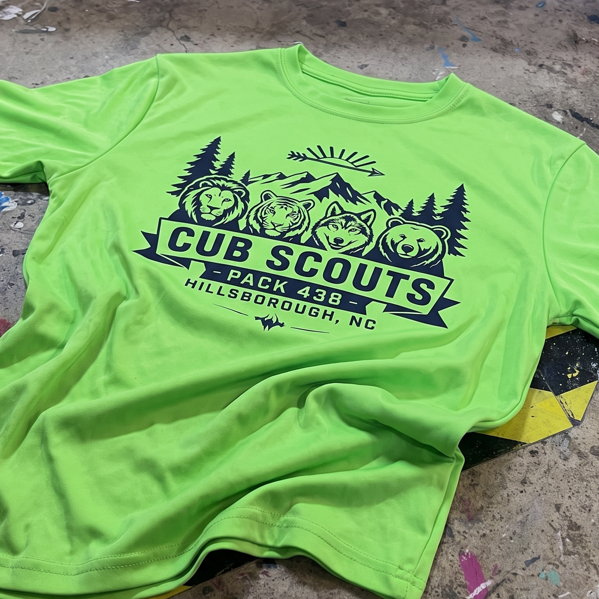 Neon green T-shirt with navy Cub Scouts Pack 438 mountain and animal graphic.