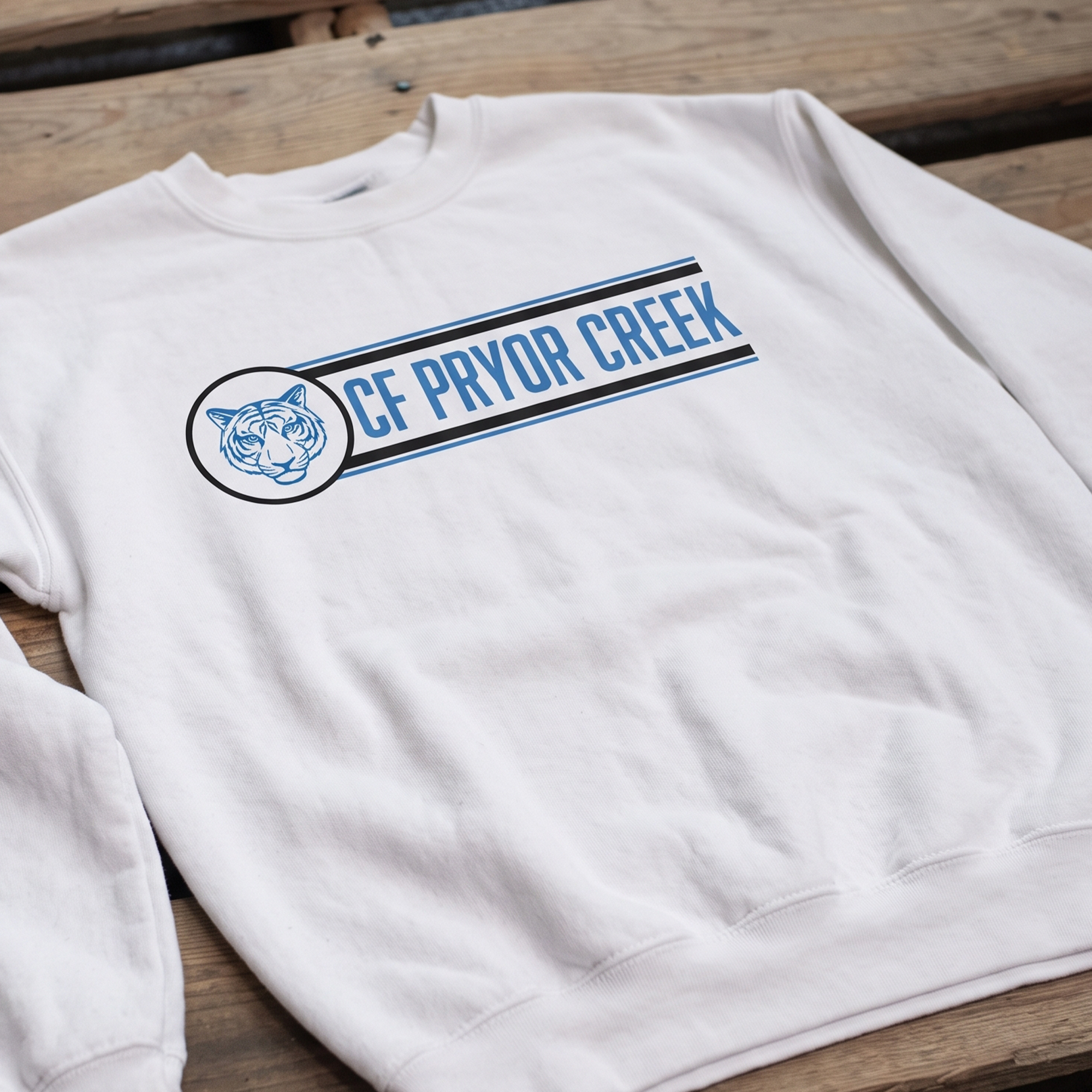 White crewneck with blue tiger emblem and Pryor Creek text.