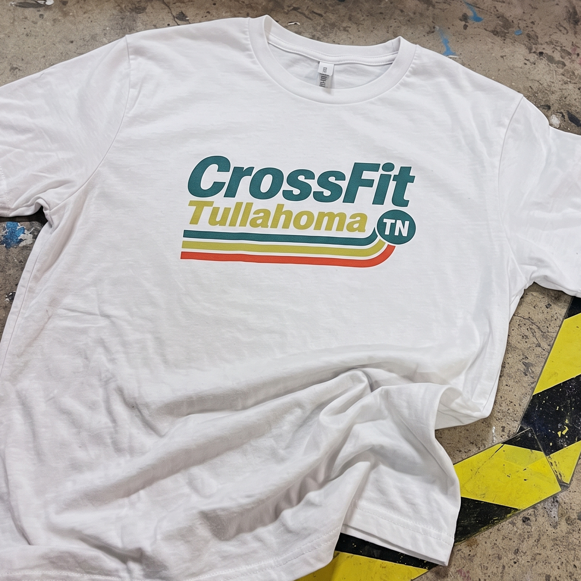White T-shirt with teal, yellow and orange CrossFit Tullahoma stripe graphic.
