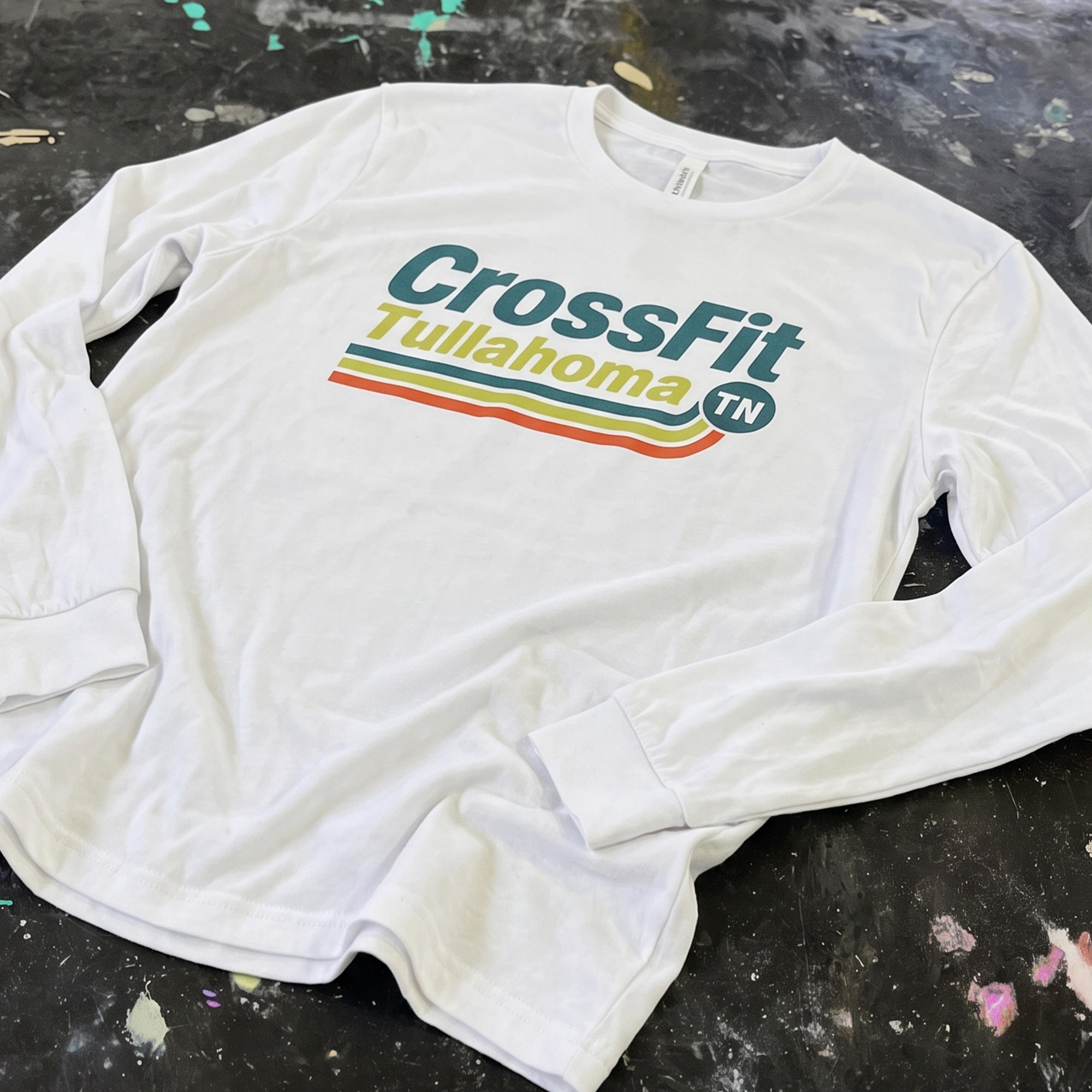 White long-sleeve shirt with teal, yellow and orange CrossFit Tullahoma stripe graphic.