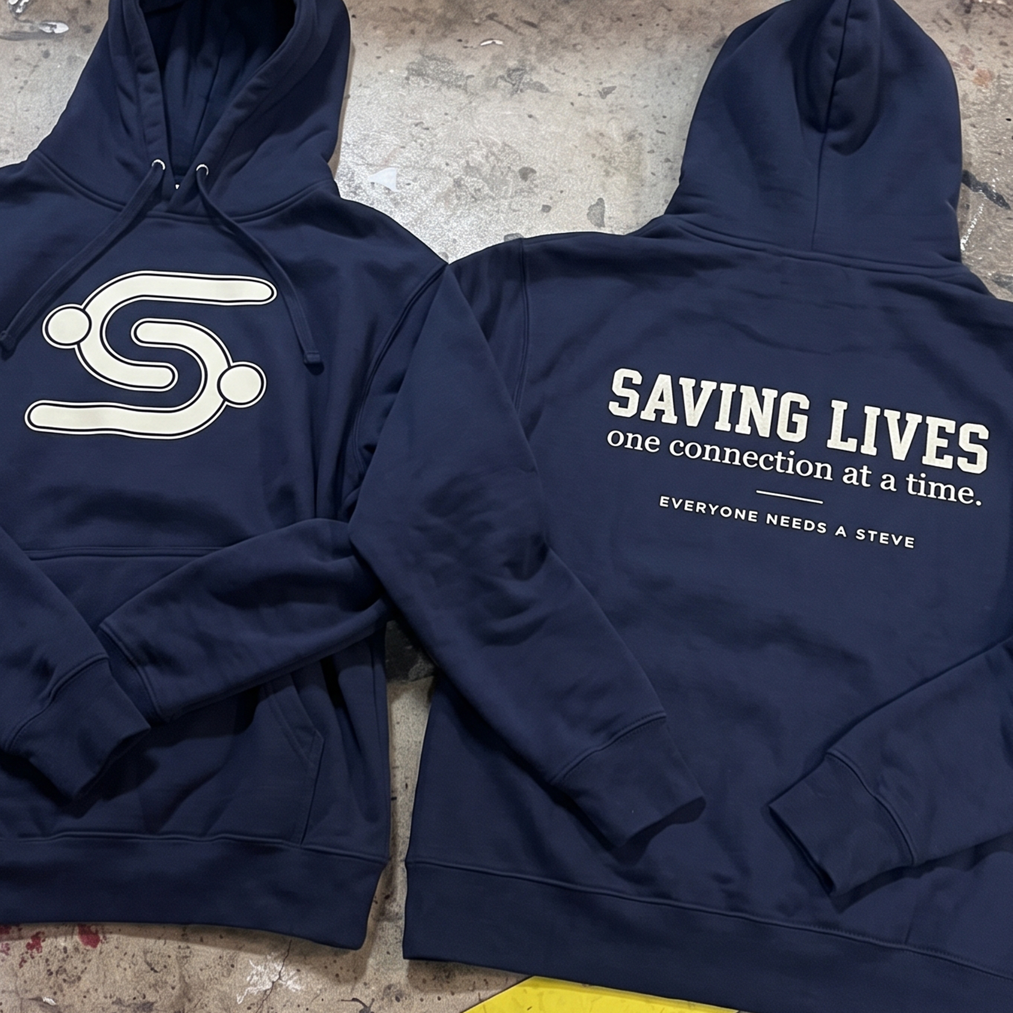 Navy hoodie with white chest logo and collegiate back print reading “Saving Lives one connection at a time.”