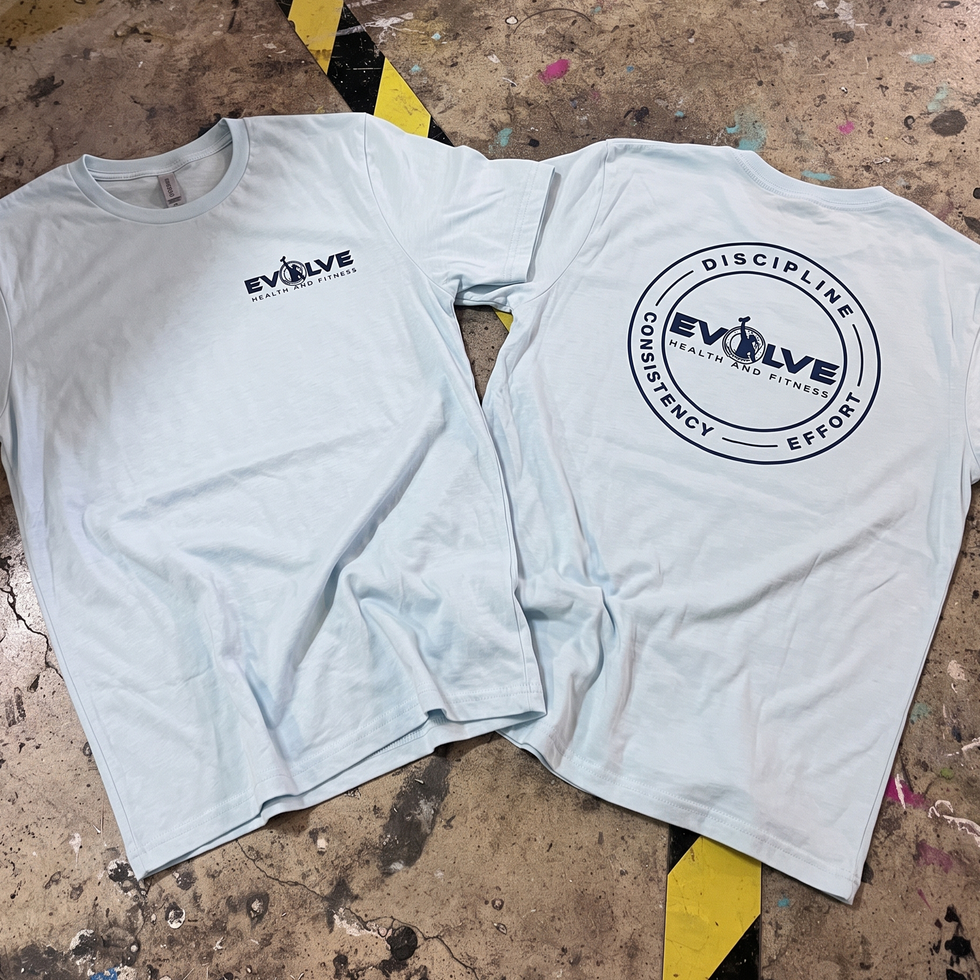 Light blue T-shirts with navy chest logo and circular back print.