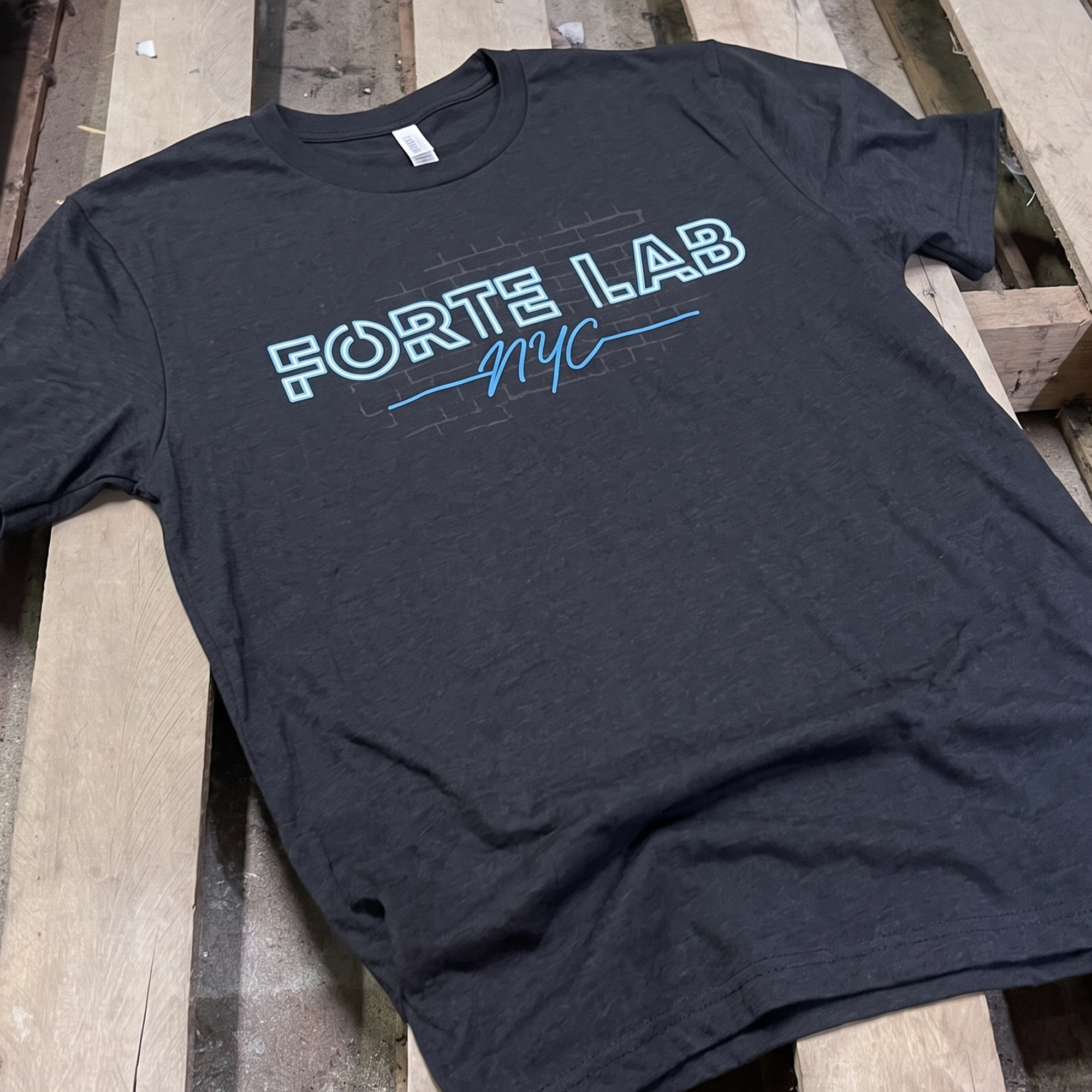 Black Forte Lab NYC T-shirt with blue outlined lettering and subtle brick graphic.