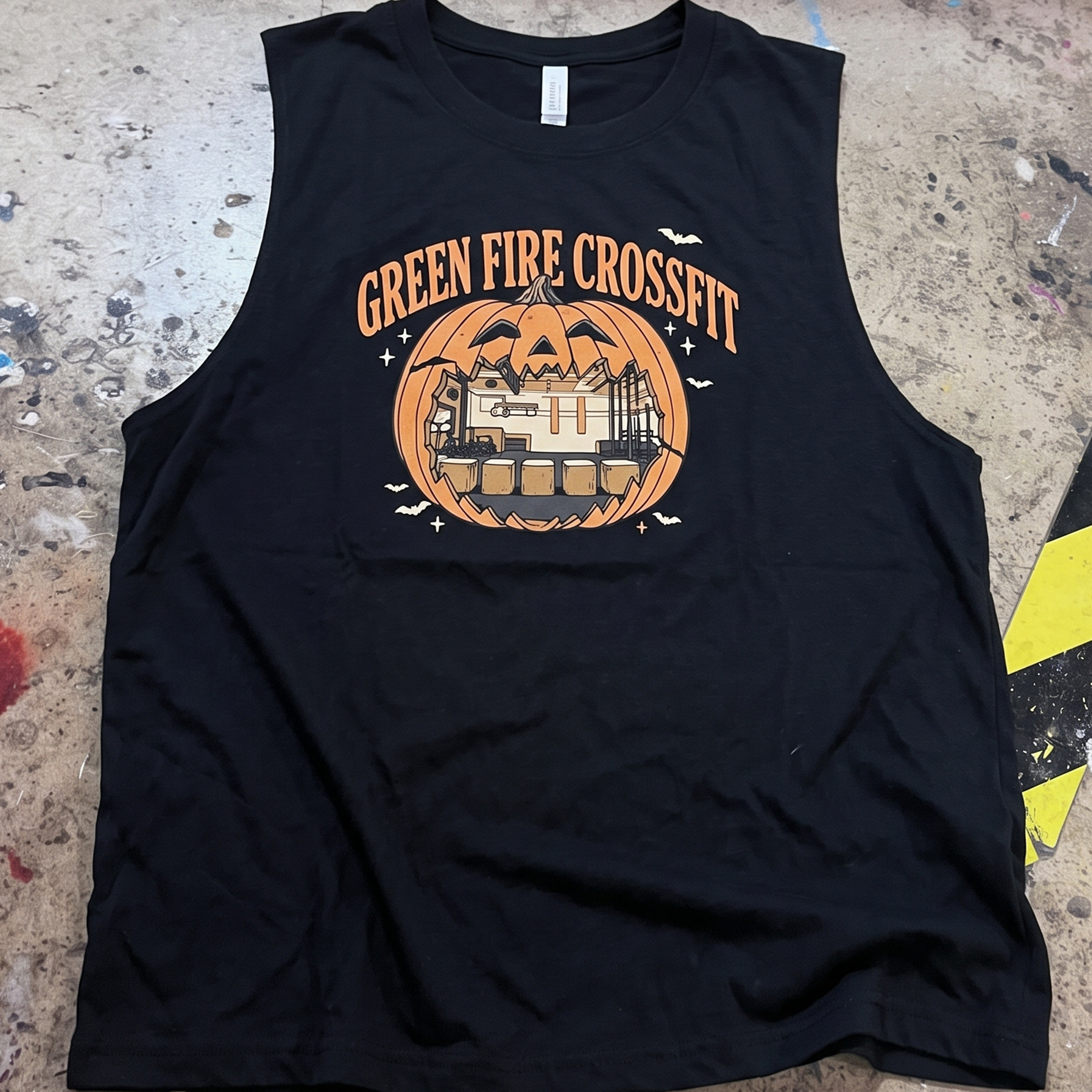 Black tank with orange pumpkin graphic framing a gym interior.