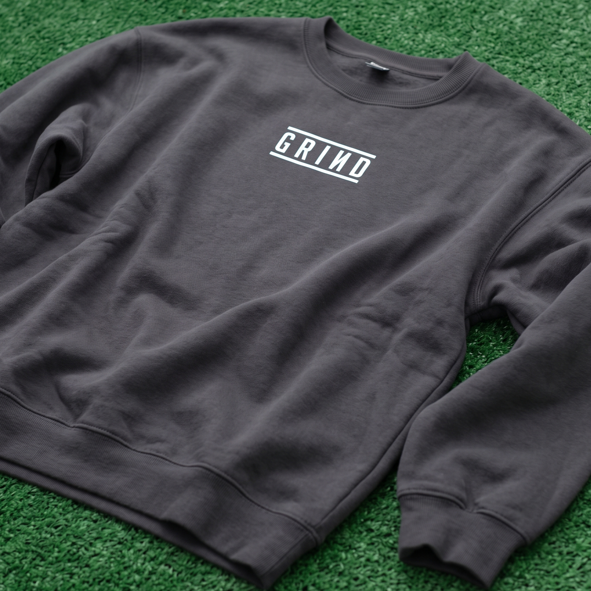 Charcoal crewneck sweatshirt with a white framed GRIND wordmark on the chest