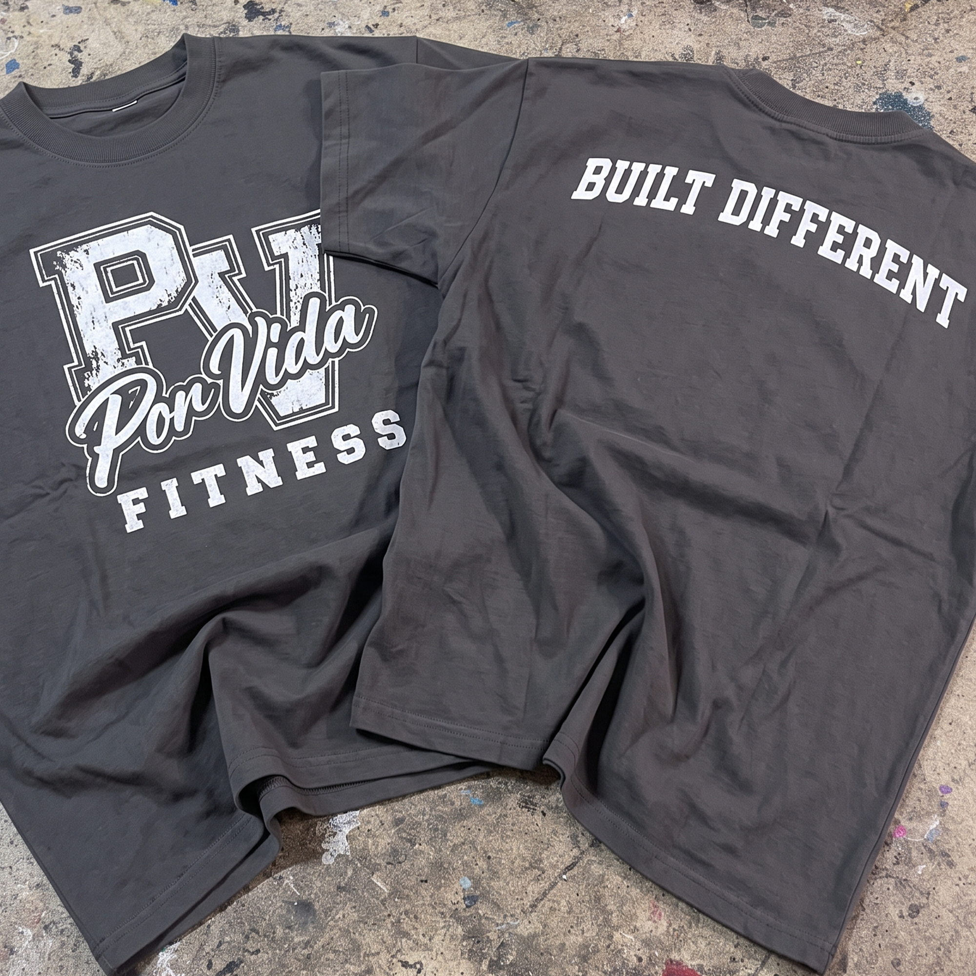Charcoal performance tees with a white distressed Por Vida Fitness front print and white Built Different back print.