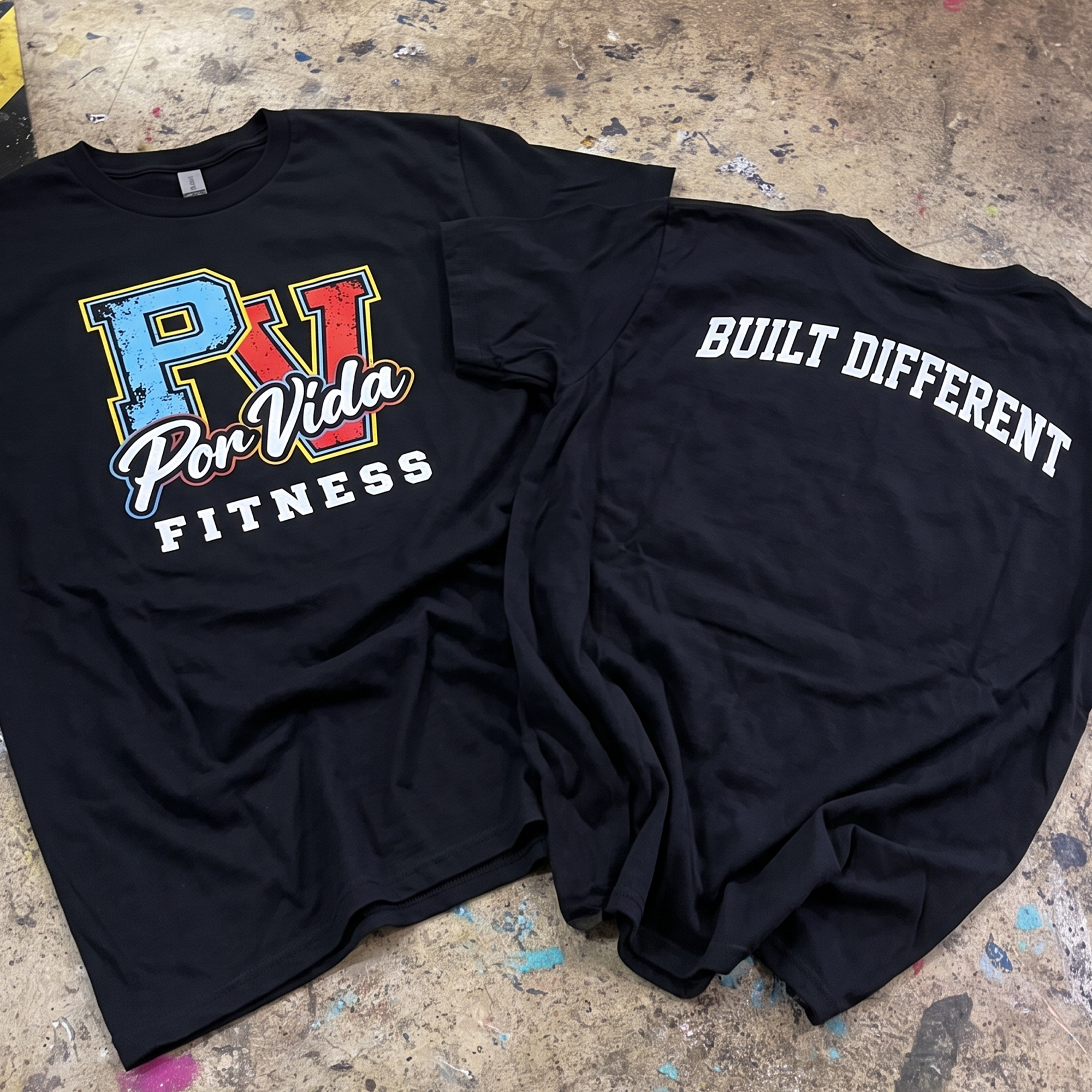 Black performance tees with a colorful distressed Por Vida Fitness front print and white Built Different back print.