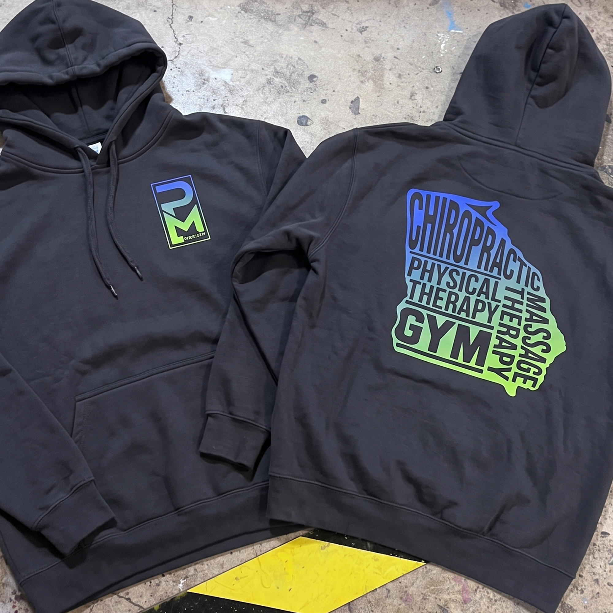 Black hoodies with gradient PM Health chest logos and large stacked back graphics.