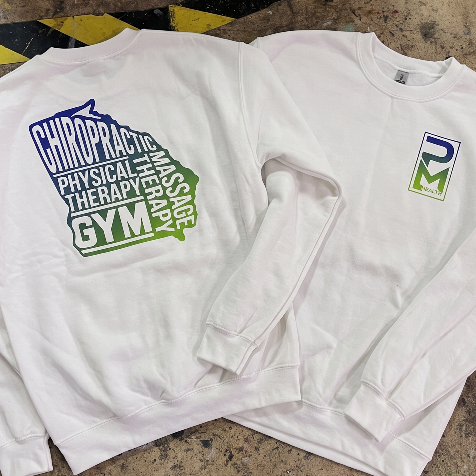 White crewneck sweatshirts with gradient PM Health chest logos and large stacked back graphics.