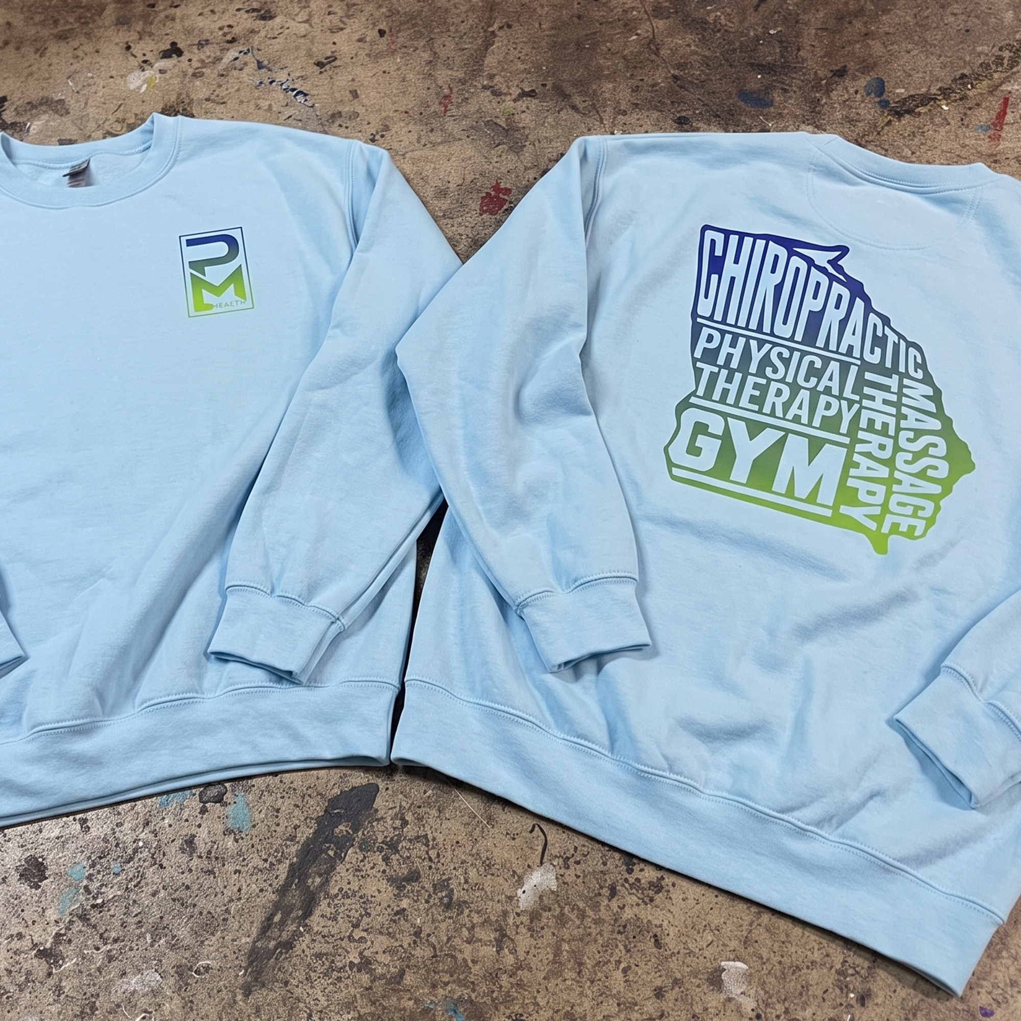 Light blue crewneck sweatshirts with gradient PM Health chest logos and large stacked back graphics.